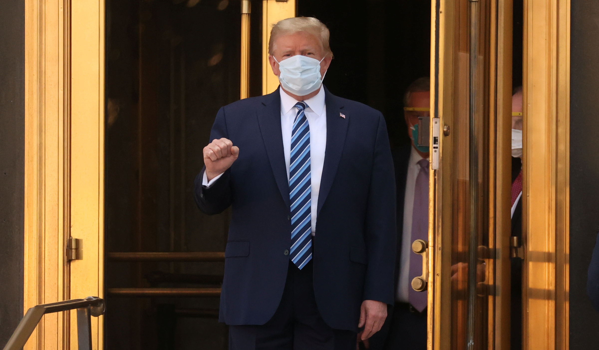 U.S. President Donald Trump makes a fist as he walks out the front doors of Walter Reed National Military Medical Center after a fourth day of treatment for the coronavirus disease (COVID-19) as he heads to the Marine One helicopter to return to the White House in Washington from the hospital in Bethesda, Maryland, U.S., October 5, 2020. REUTERS