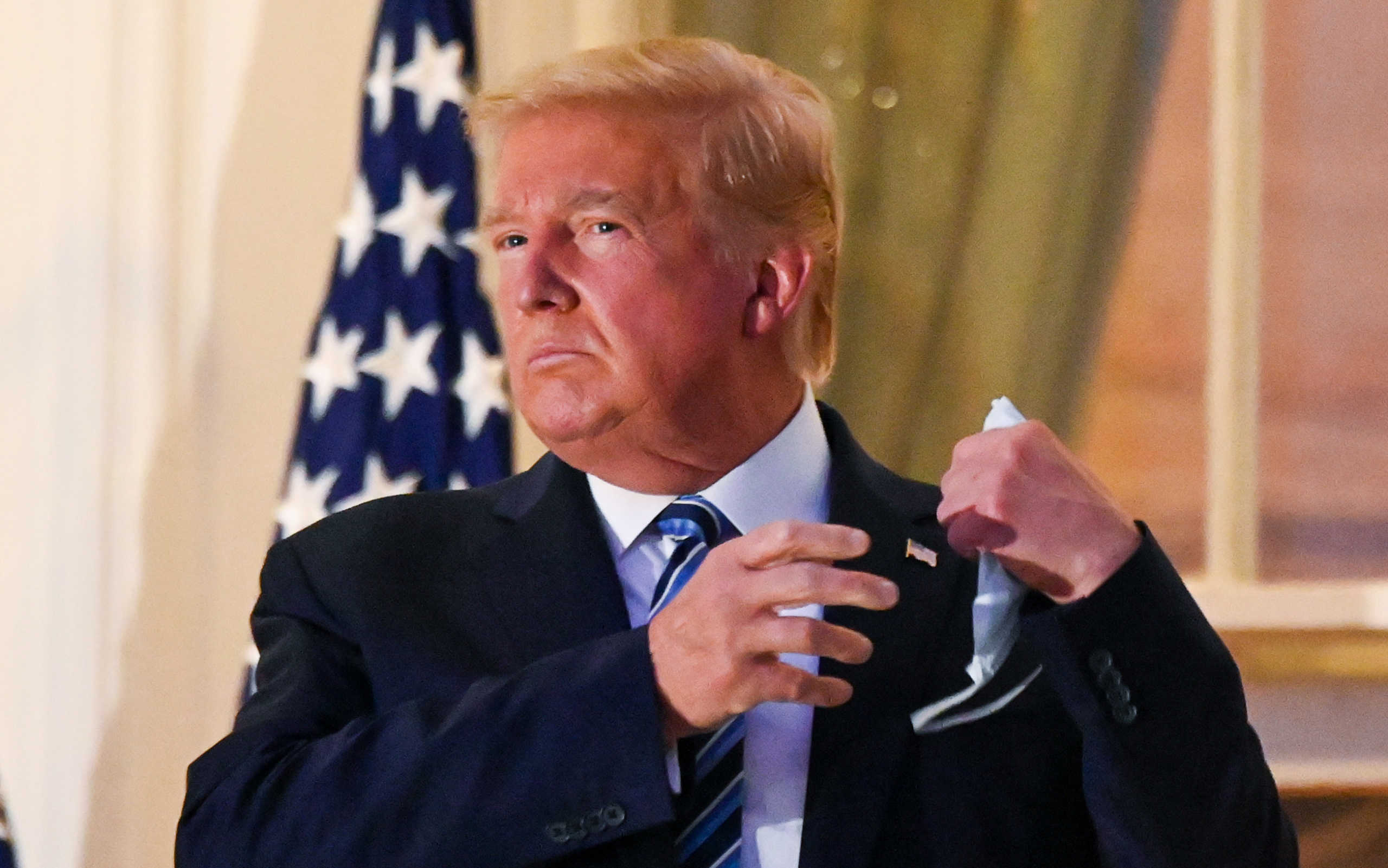 U.S. President Donald Trump pulls off his protective face mask as he poses atop the Truman Balcony of the White House after returning from being hospitalized at Walter Reed Medical Center for coronavirus disease (COVID-19) treatment, in Washington, U.S. October 5, 2020. REUTERS