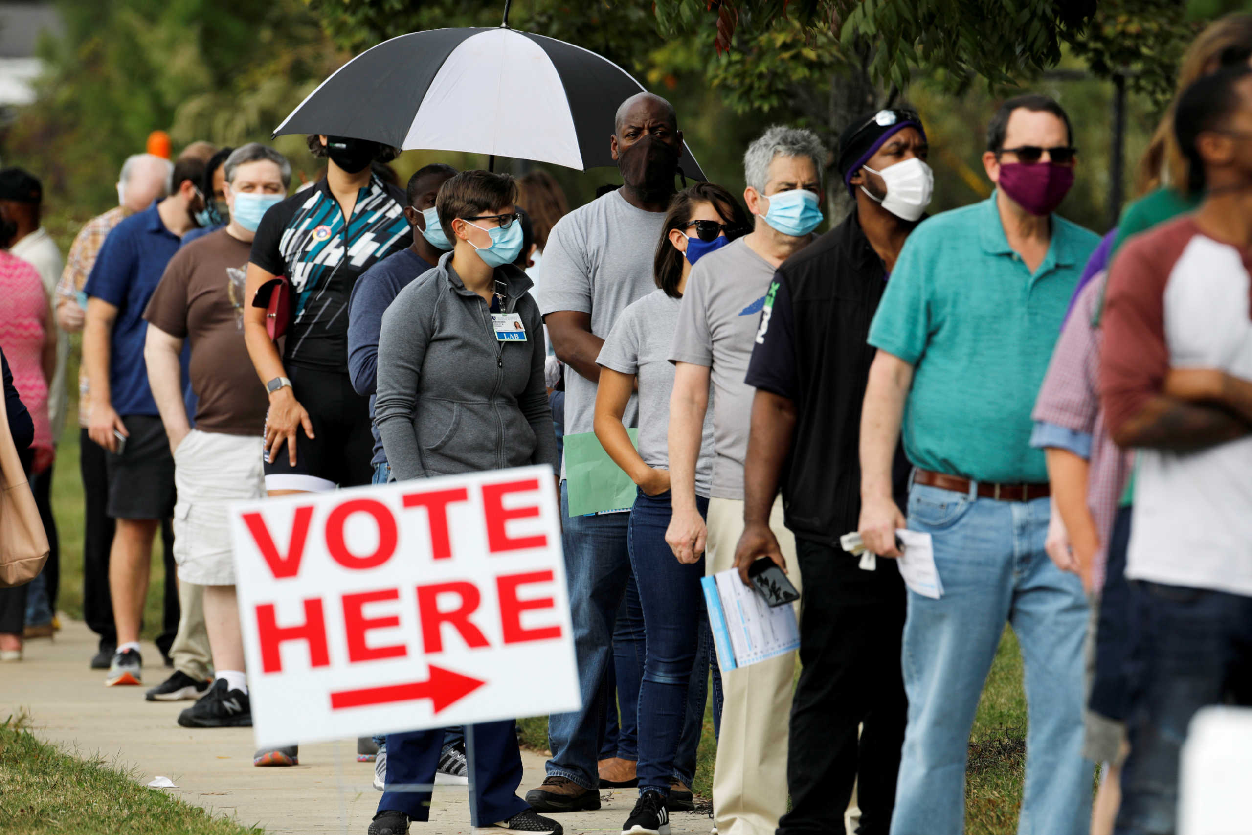 Voters wait in line to enter a polling place and cast their ballots on the first day of the state's in-person early voting for the general elections in Durham, North Carolina, U.S. October 15, 2020.    REUTERS