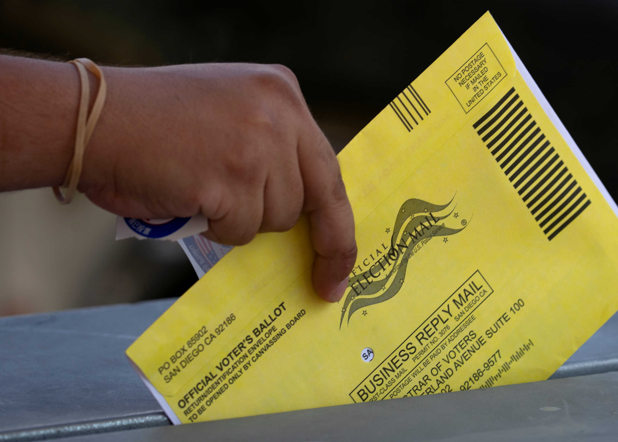 FILE PHOTO: An election worker places mail-in ballots into a voting box at a drive-through drop off location at the Registrar of Voters for San Diego County in San Diego, California, U.S., October 19, 2020. REUTERS