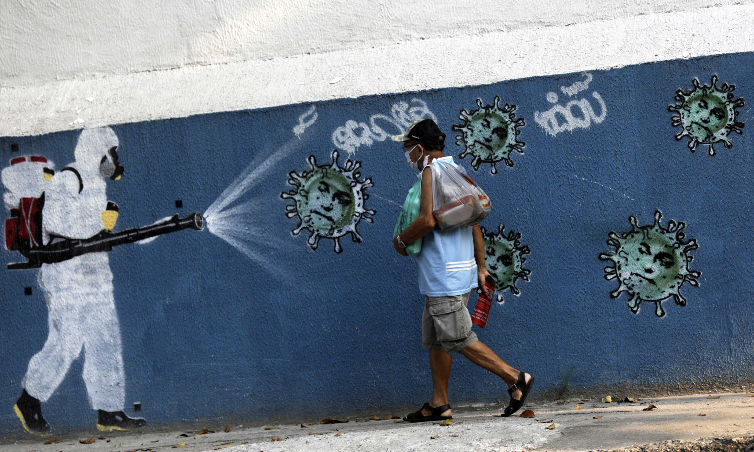 A man walks next to graffiti depicting a cleaner in protective gear spraying viruses with the face of Brazil's President Jair Bolsonaro, amid the coronavirus disease (COVID-19) outbreak, in Rio de Janeiro, Brazil, October 7, 2020. REUTERS