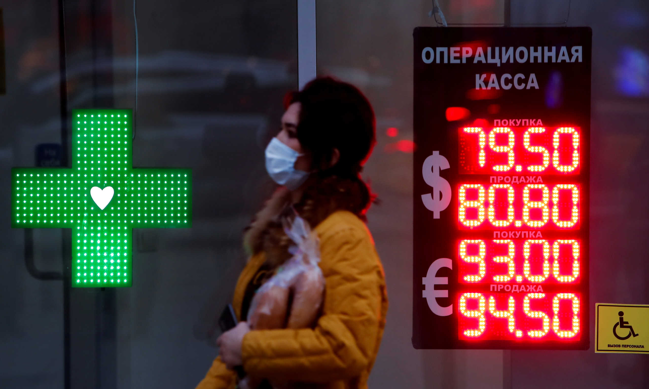 FILE PHOTO: Woman walks past a board showing currency exchange rates of the euro and U.S. dollar against the Russian rouble in Moscow, Russia November 2, 2020. REUTERS
