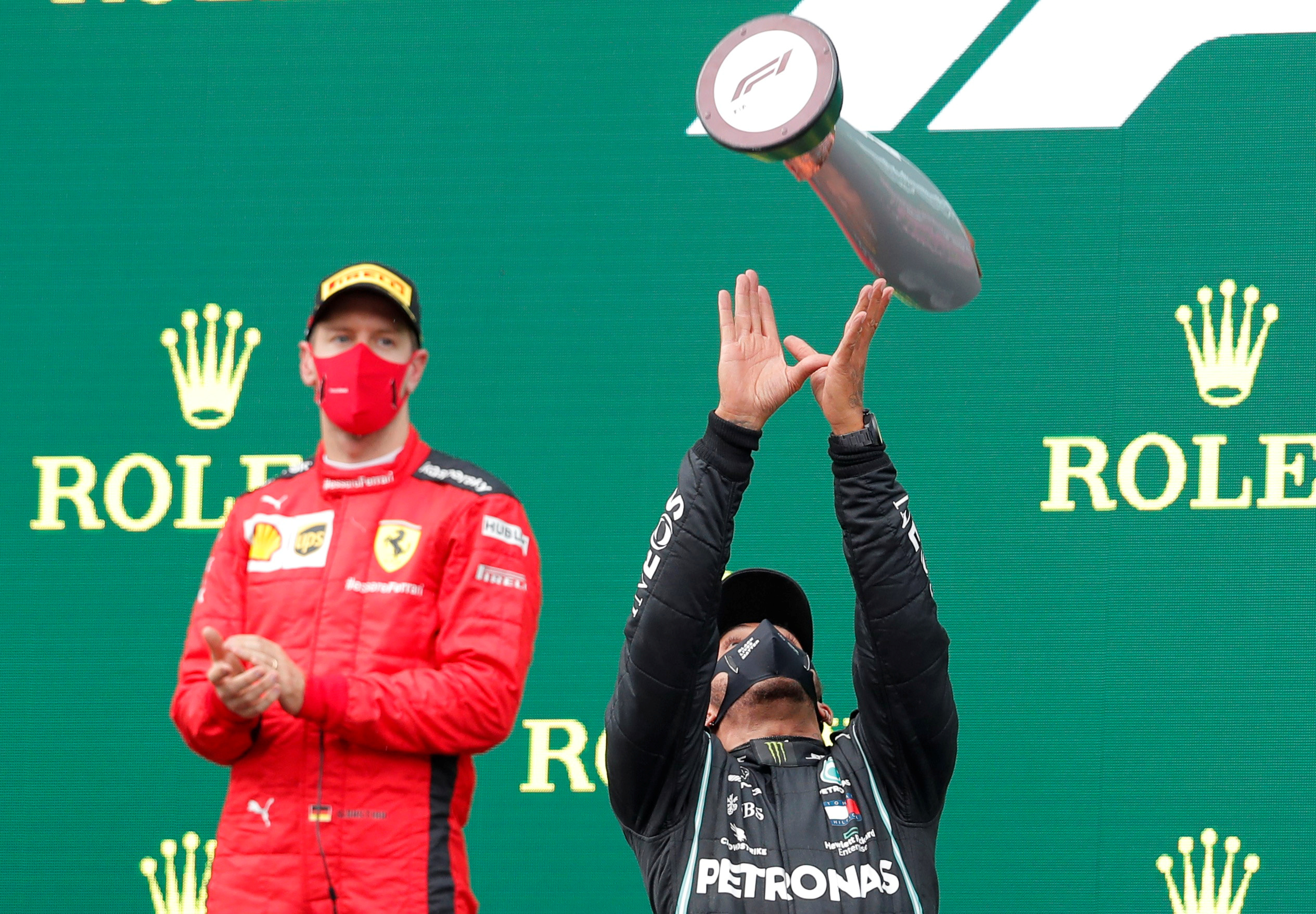 Formula One F1 - Turkish Grand Prix - Istanbul Park, Istanbul, Turkey - November 15, 2020 Mercedes' Lewis Hamilton celebrates on the podium with a trophy after winning the race alongside third placed Ferrari's Sebastian Vettel Pool via REUTERS