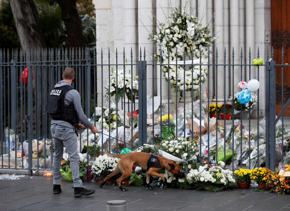 A police officer with a sniffer dog check flowers in front of Notre Dame basilica, before a mass to pay tribute to the victims of a deadly knife attack in Nice, France, November 1, 2020. REUTERS