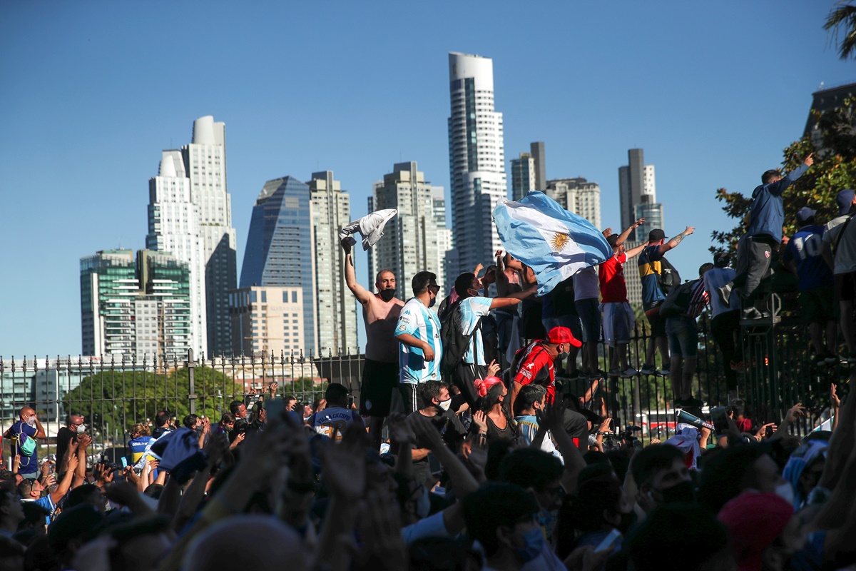 People climb on the fence of the Casa Rosada presidential palace as they gather to mourn the death of soccer legend Diego Armando Maradona, in Buenos Aires, Argentina, November 26, 2020. REUTERS