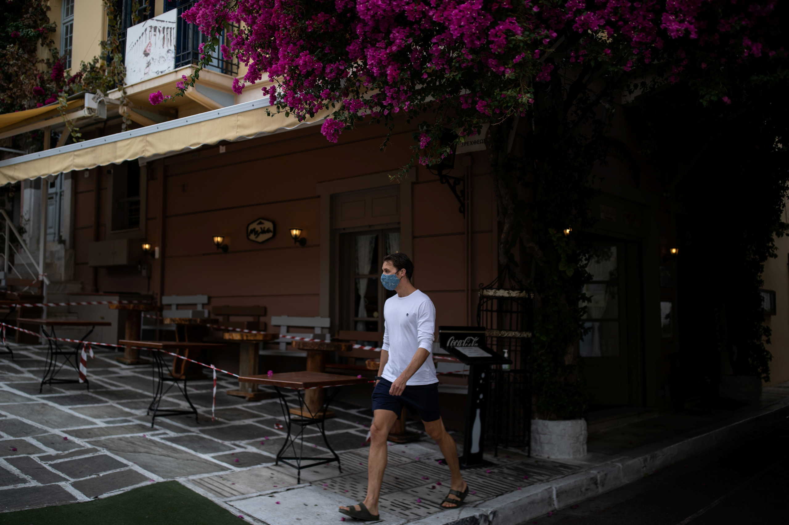 A man wearing a protective face mask makes his way next to a closed restaurant in Plaka district, amid the coronavirus disease (COVID-19) pandemic, in Athens, Greece, November 3, 2020. REUTERS