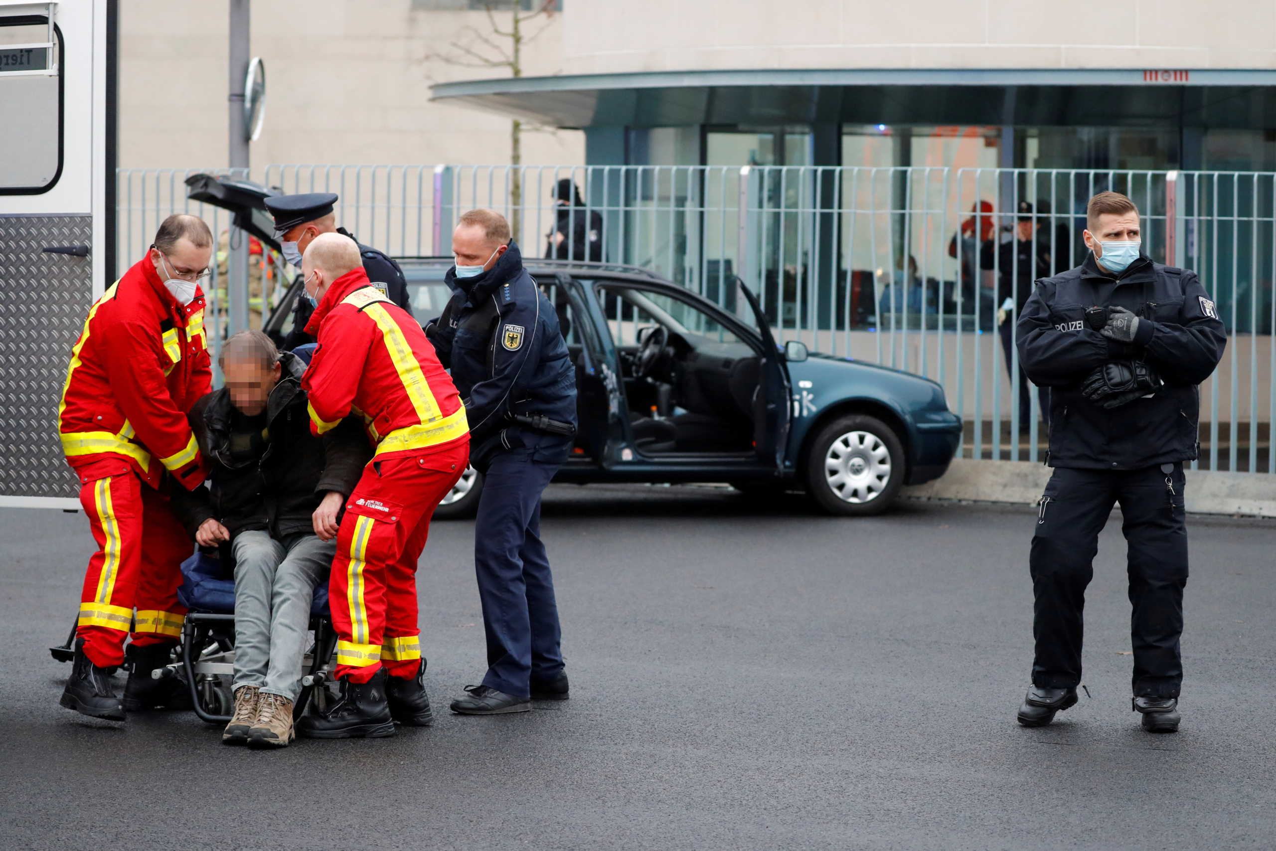 Firefighters attend a man who crashed with his car into the main gate of the chancellery in Berlin, the office of German Chancellor Angela Merkel in Berlin, Germany, November 25, 2020. The man's face is pixelated for privacy reasons. REUTERS