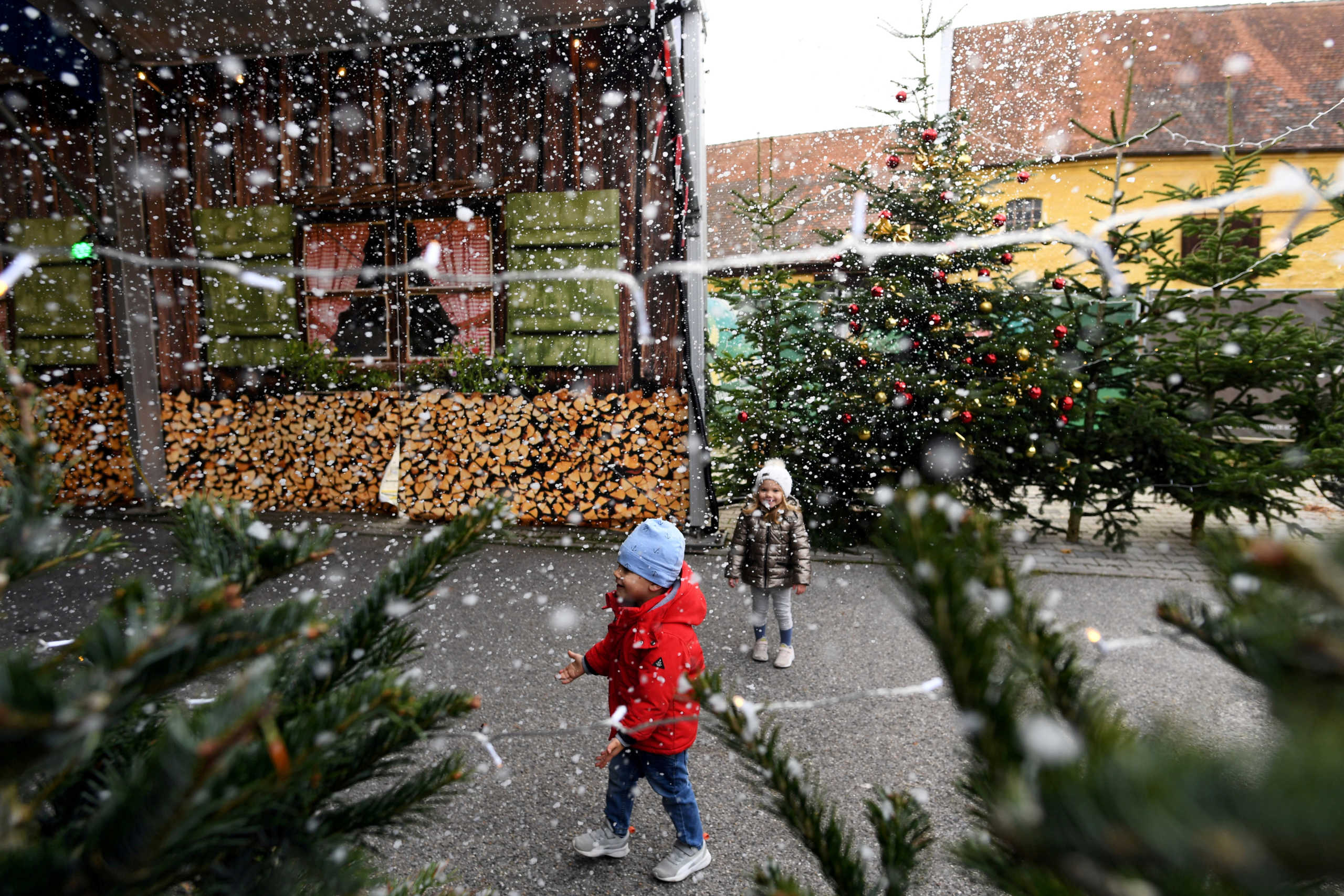 FILE PHOTO: Mila and Lion play with artificial snowflakes at a drive-in Christmas market under a large marquee, amid the spread of the coronavirus disease (COVID-19), in Landshut, Germany, November 12, 2020. REUTERS