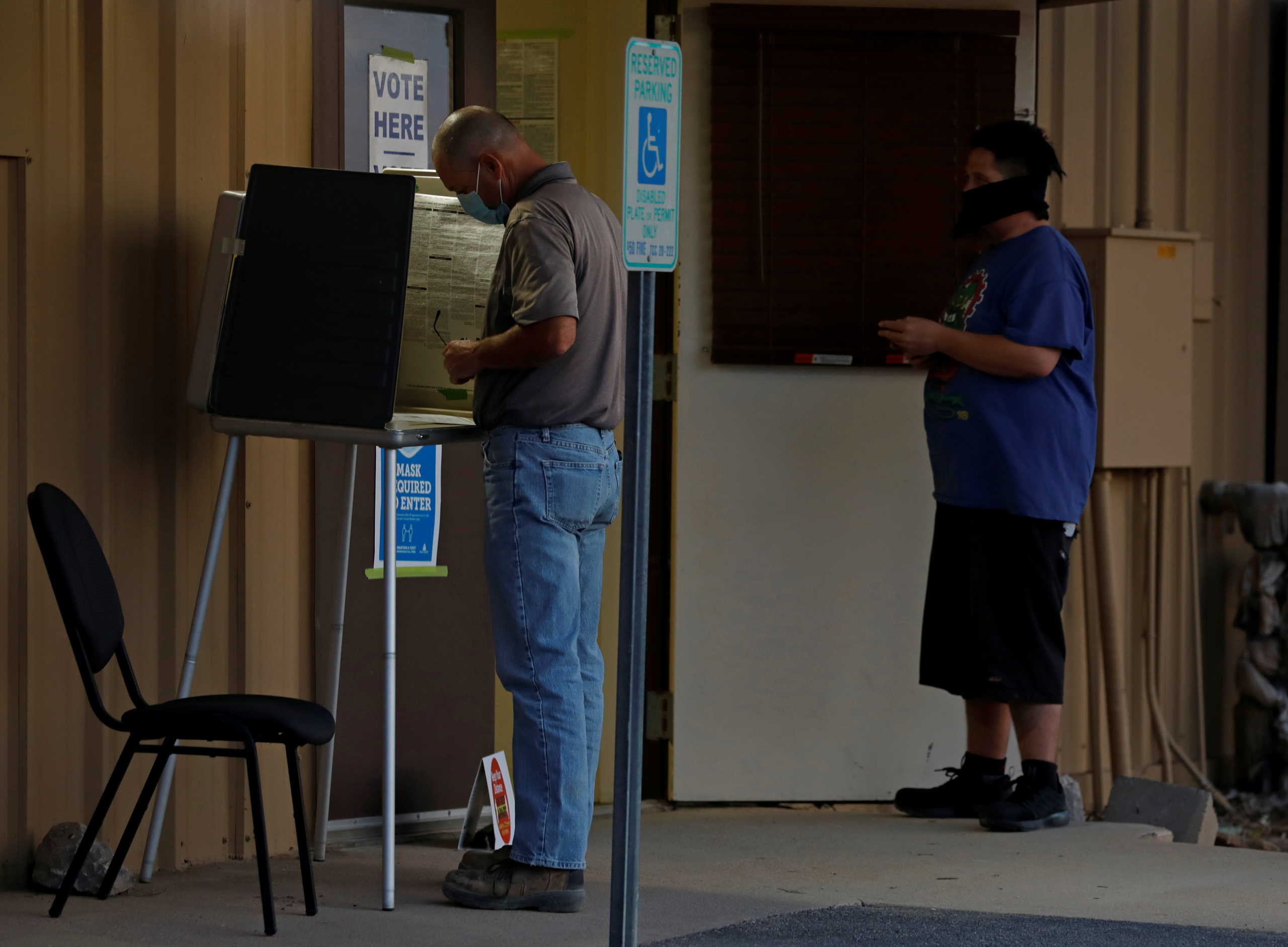 A voter fills in his ballot at a polling booth as another voter waits in line, on Election Day at a polling station in Marana, Arizona, U.S. November 3, 2020.  REUTERS