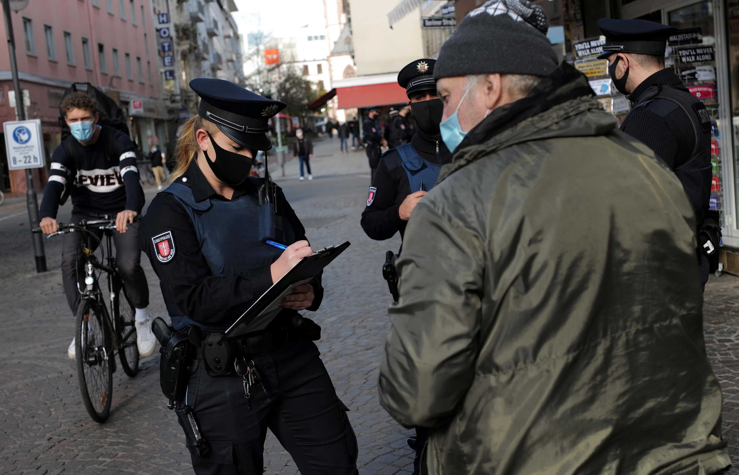 City police officers impose a fine to a man who was not wearing a mandatory mouth and nose cover during their patrol as the spread of coronavirus disease (COVID-19) continues in Frankfurt, Germany, November 2, 2020. REUTERS