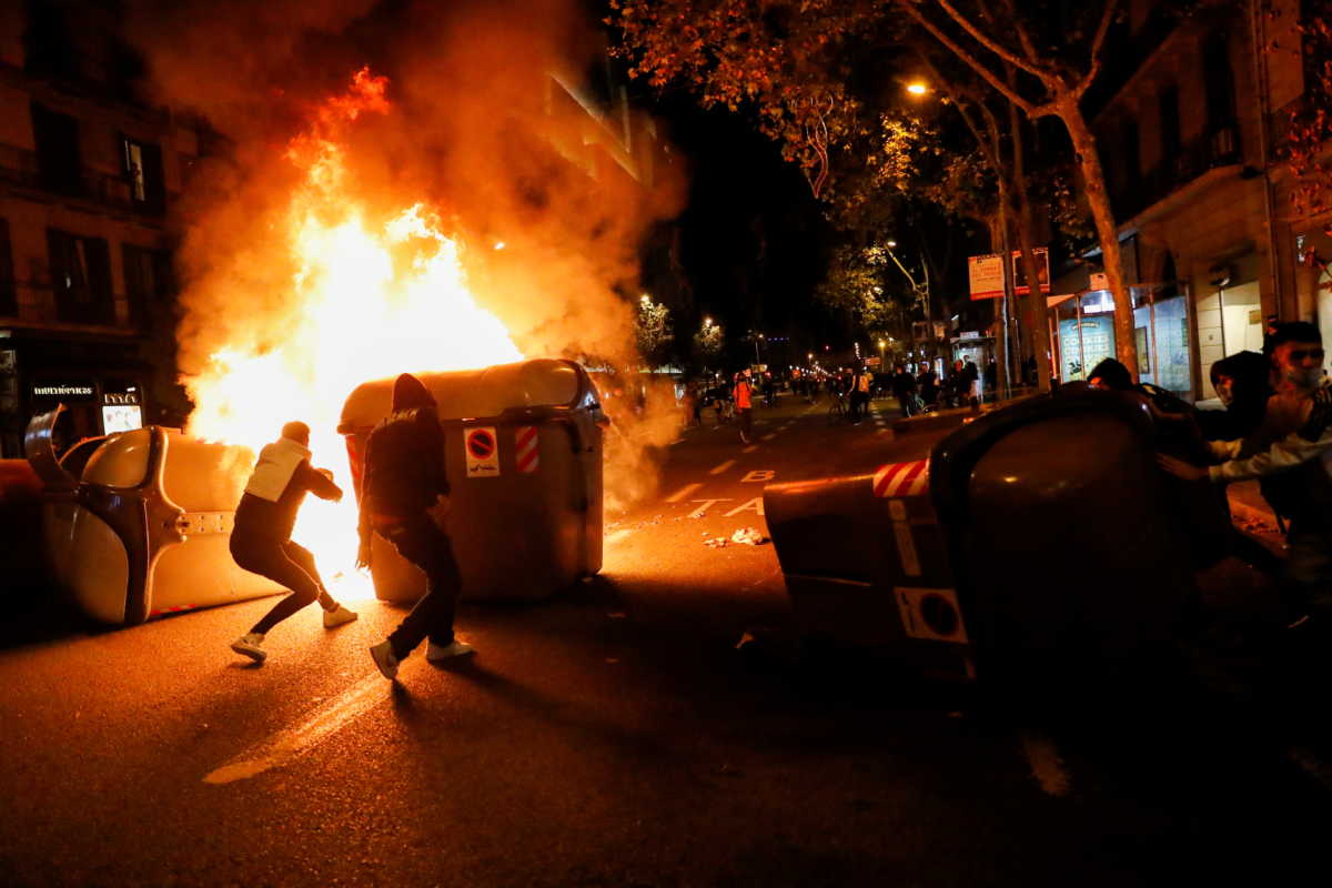 Demonstrators stand behind a burning barricade during a protest against the closure of bars and gyms, amidst the coronavirus disease (COVID-19) outbreak, in Barcelona, Spain October 30, 2020. REUTERS