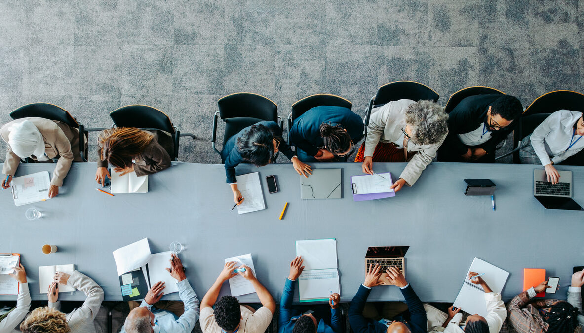Top view of diverse business group in office meeting, collaborating and discussing around a large table.