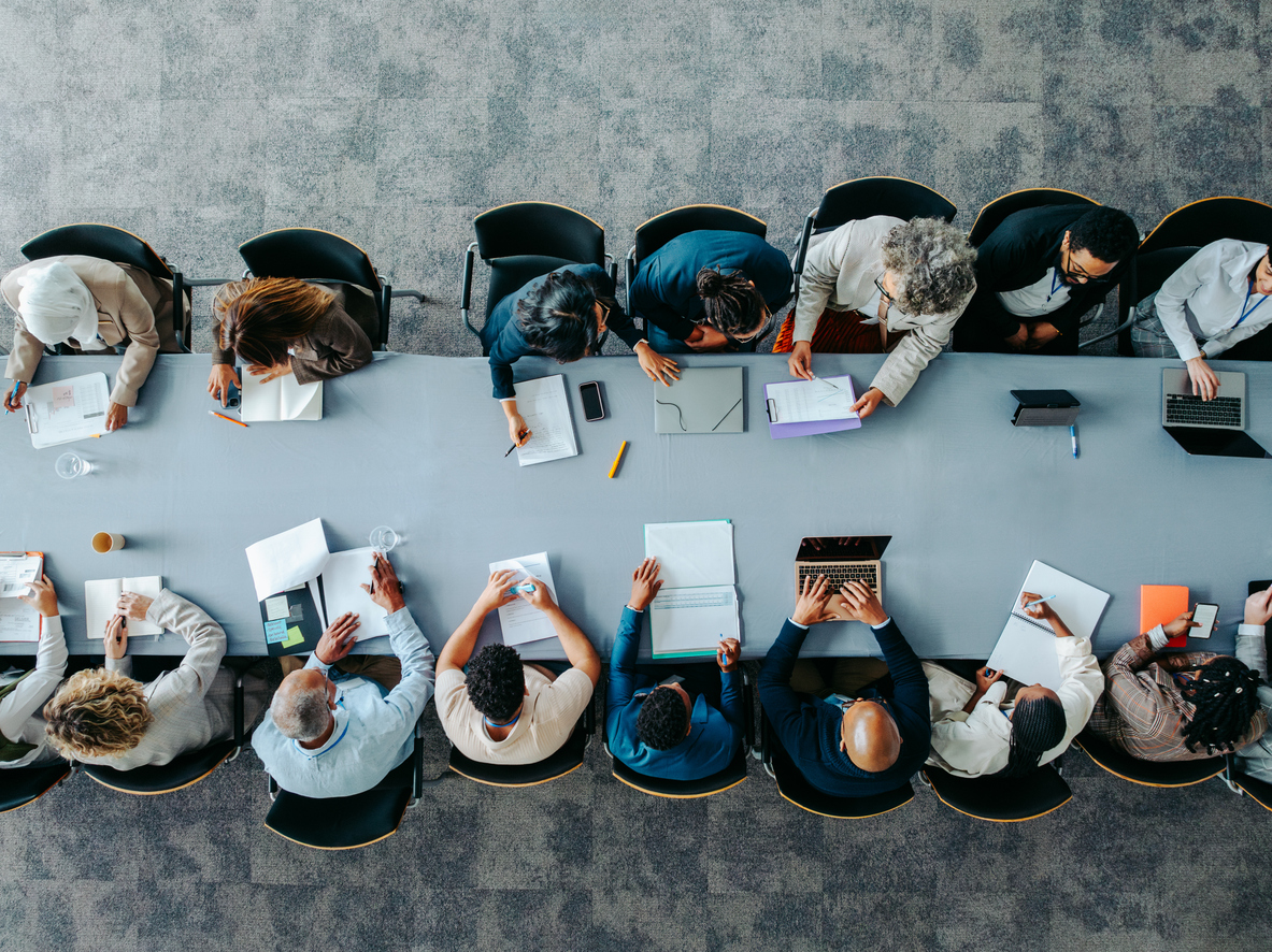 Top view of diverse business group in office meeting, collaborating and discussing around a large table.