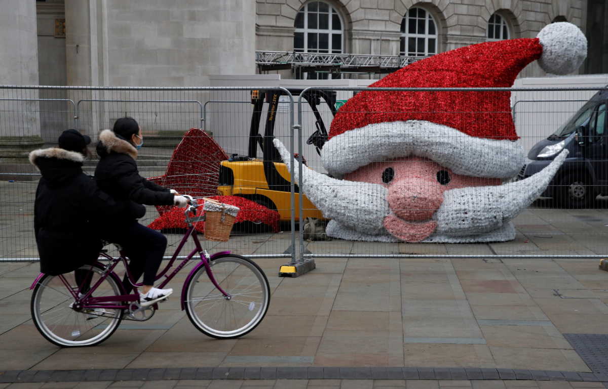People cycle past the head of a giant Santa Claus statue as it waits to be lifted into position amid the outbreak of the coronavirus disease (COVID-19) in Manchester, Britain, November 29, 2020. REUTERS