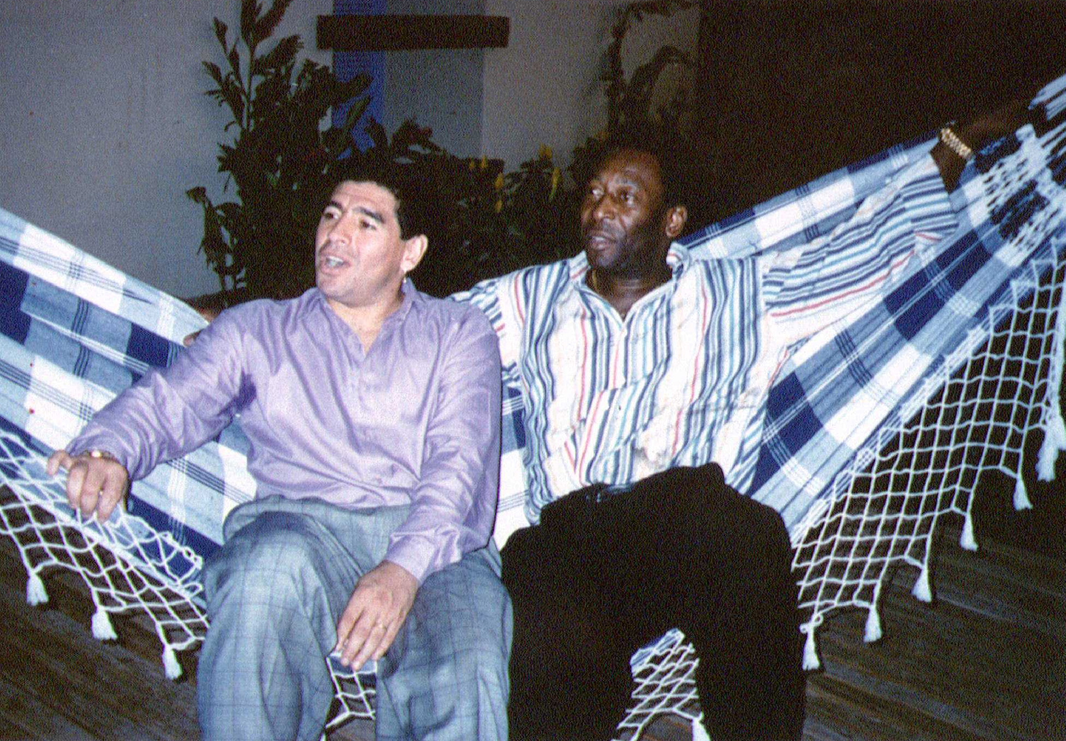 FILE PHOTO: Soccer legends Diego Maradona (L) and Pele rest on a hammock during a reception in Rio de Janeiro, May 14, 1995.  REUTERS