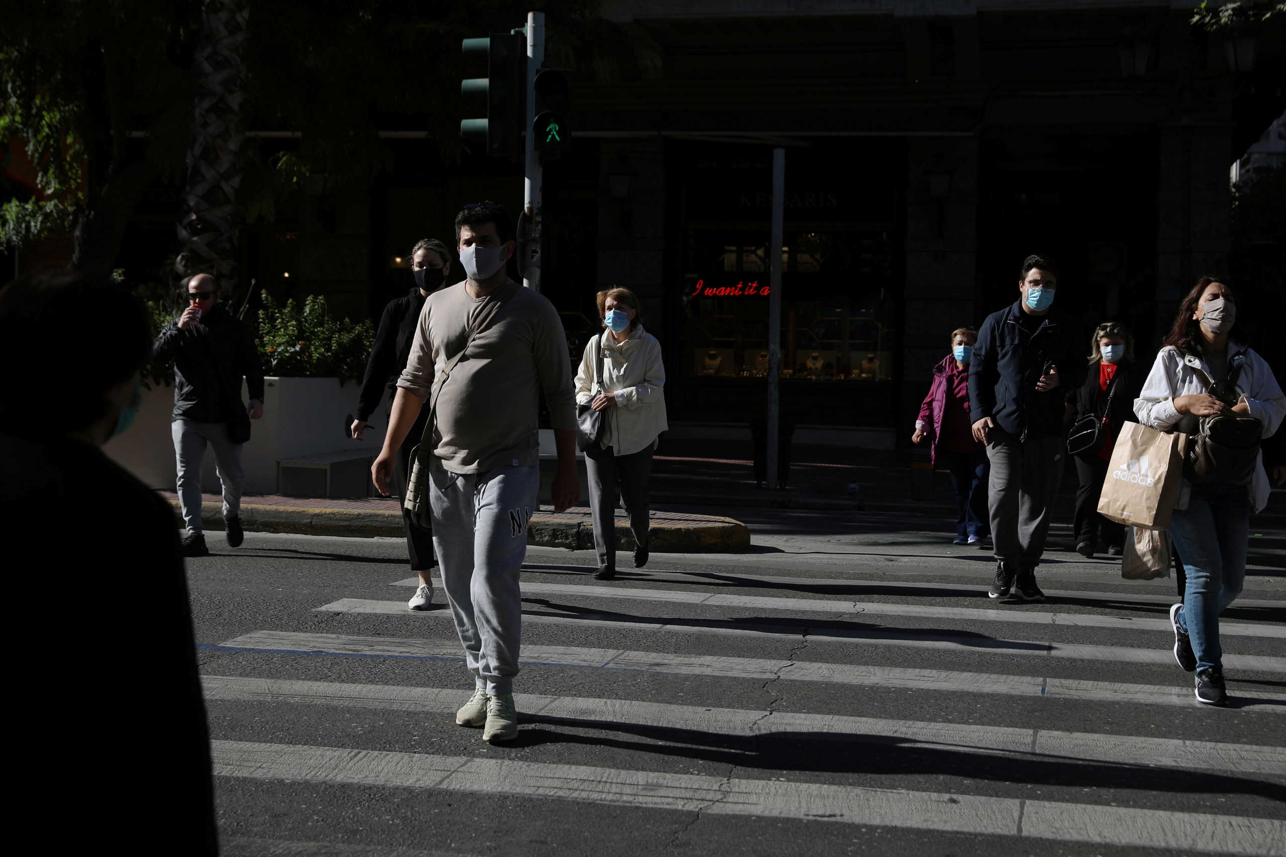Pedestrians wearing protective face masks walk on a zebra crossing, amid the spread of the coronavirus disease (COVID-19), in Athens, Greece, October 31, 2020. REUTERS