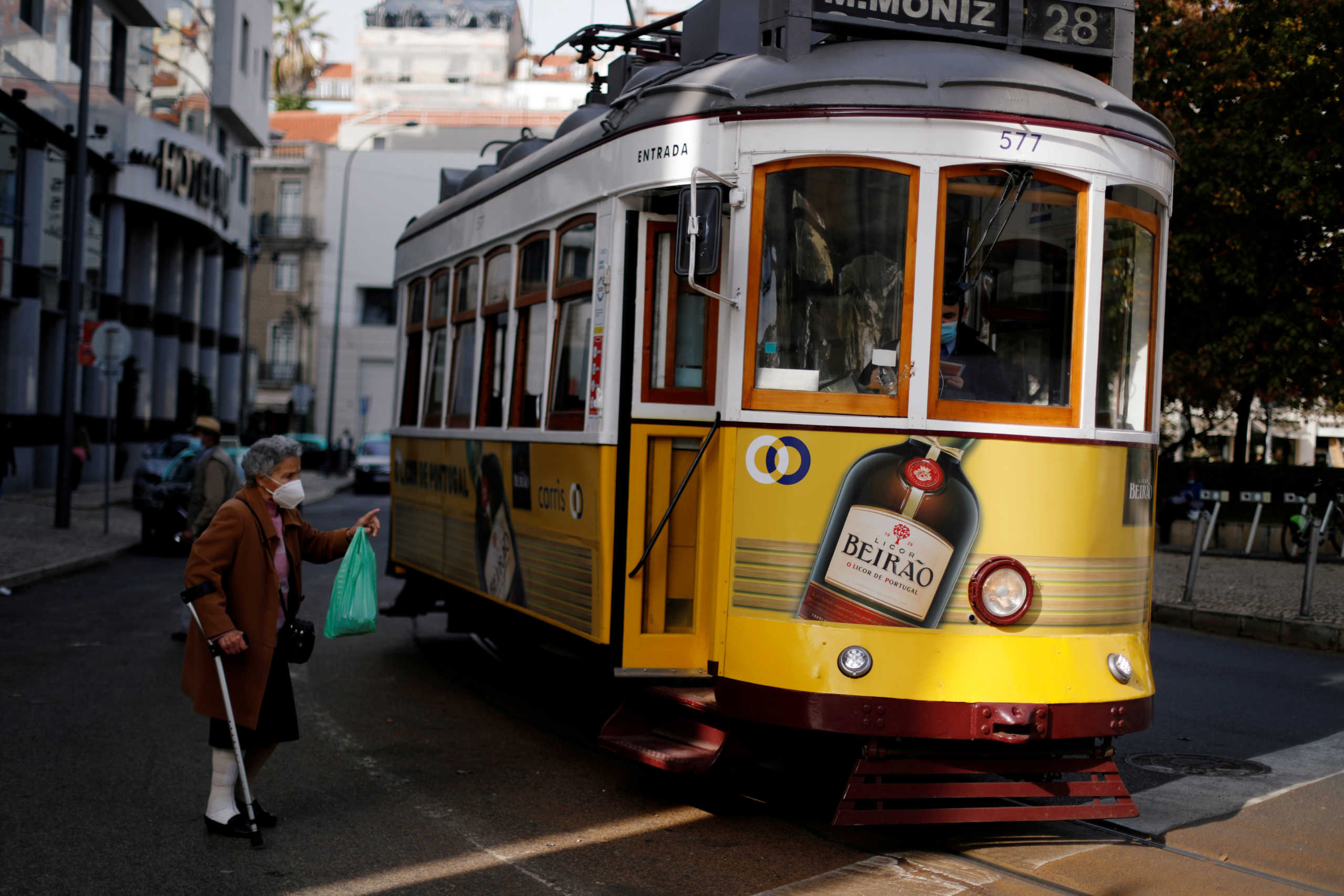 FILE PHOTO: A woman wearing a protective mask speaks with a driver of a tram during the coronavirus disease (COVID-19) outbreak, in downtown Lisbon, Portugal October 31, 2020.  REUTERS