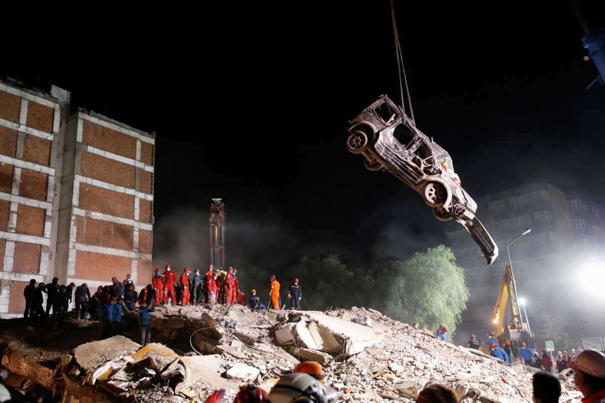 A crane lifts a vehicle as rescue operations take place on a site secured by the police after an earthquake struck the Aegean Sea, in the coastal province of Izmir, Turkey, November 1, 2020. REUTERS