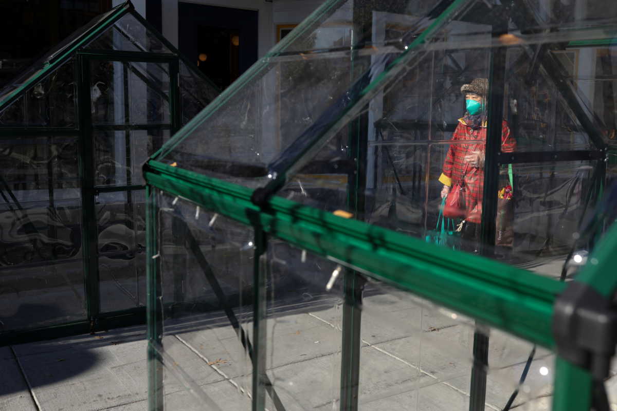 A pedestrian passes by improvised dining tents outside of a restaurant along 14th Street, amid the COVID-19 pandemic in Washington, U.S., November 24, 2020. REUTERS