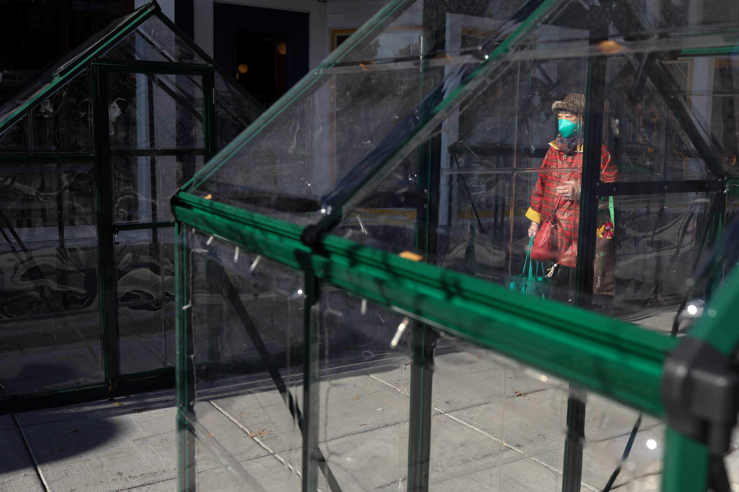 A pedestrian passes by improvised dining tents outside of a restaurant along 14th Street, amid the COVID-19 pandemic in Washington, U.S., November 24, 2020. REUTERS