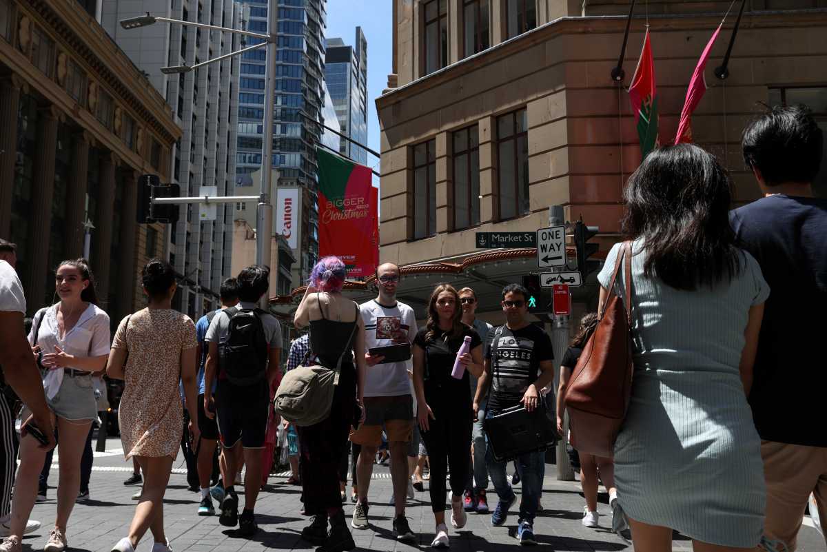 People cross a busy street under holiday decorations in the city centre of Sydney, Australia, December 17, 2020.  REUTERS