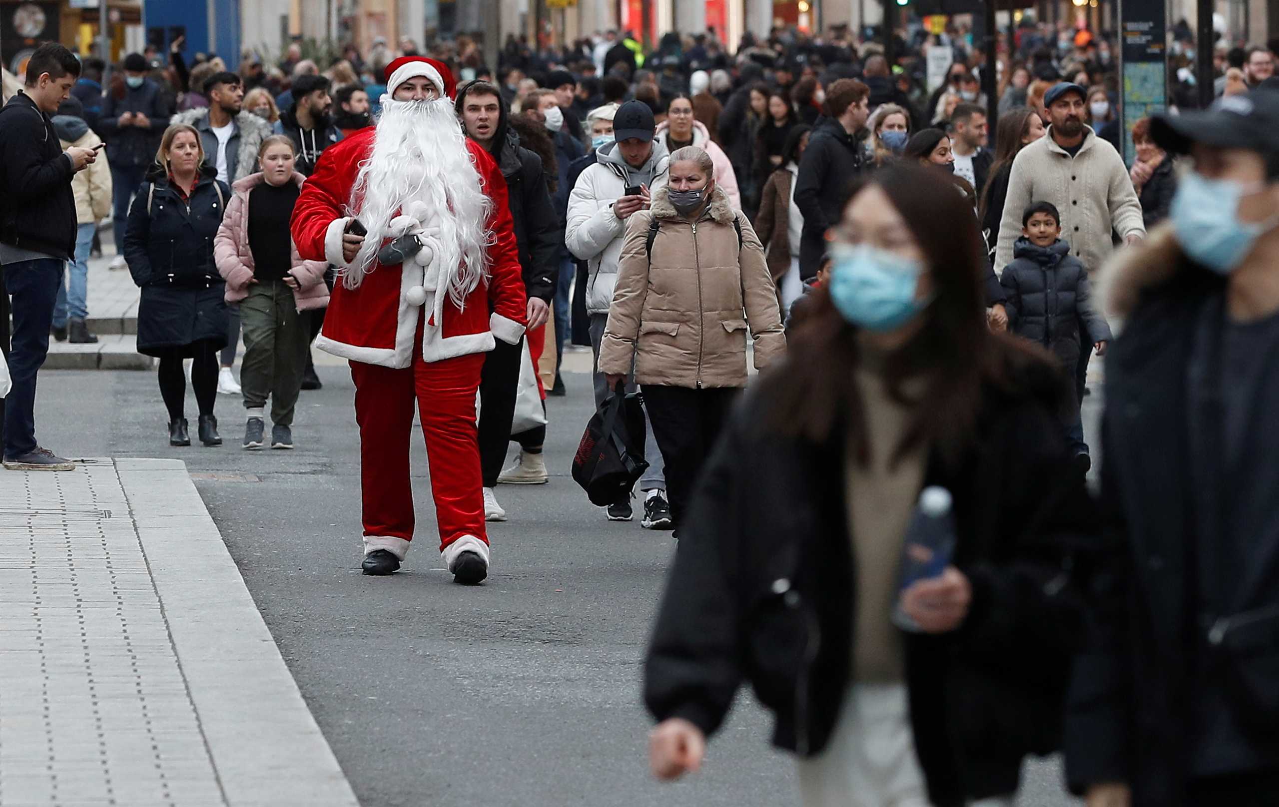 A man dressed as Santa Claus walks among shoppers on Regent street, amid the coronavirus disease (COVID-19) outbreak in London, Britain, December 12, 2020.  REUTERS