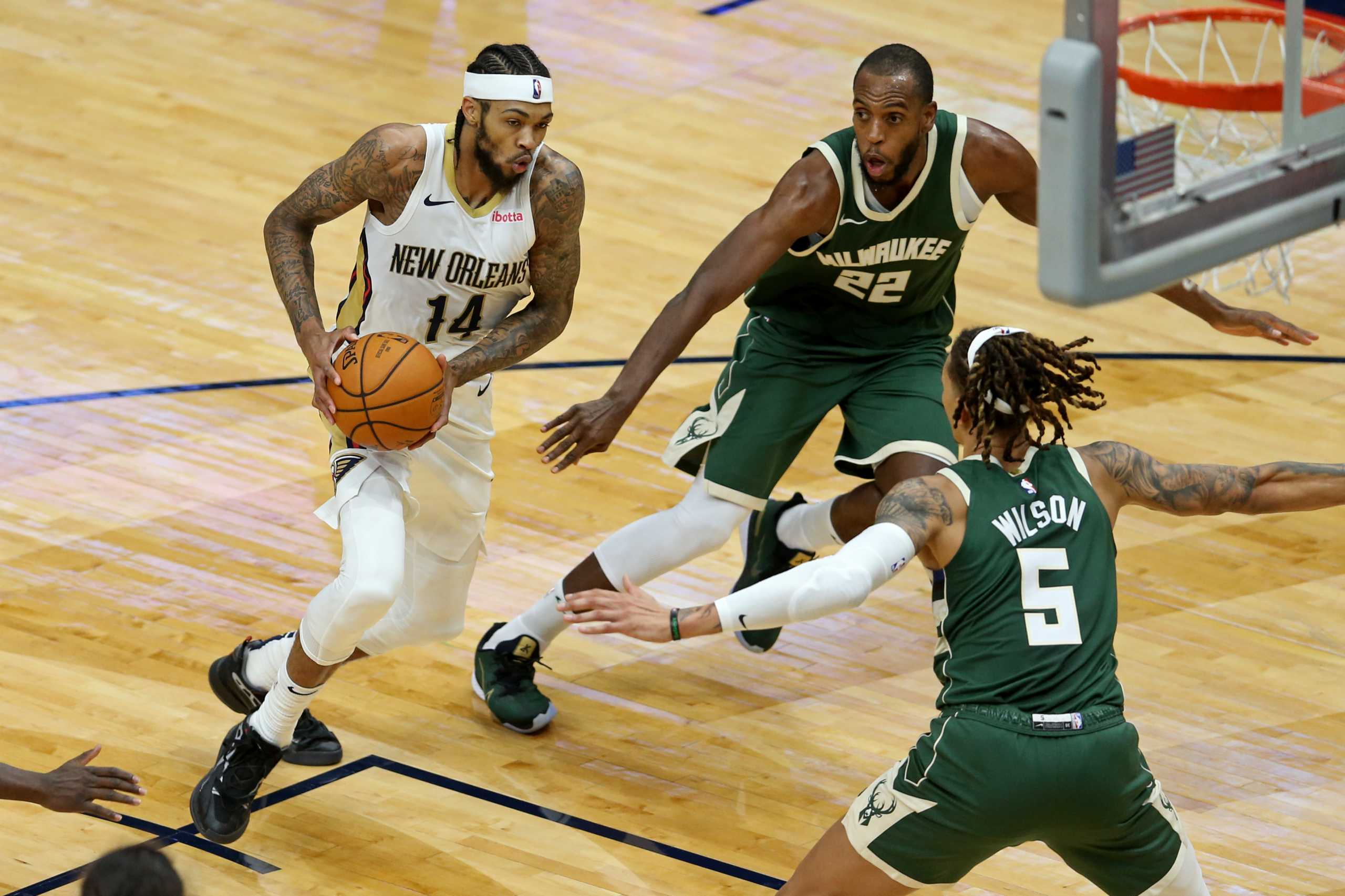 Dec 18, 2020; New Orleans, Louisiana, USA; New Orleans Pelicans forward Brandon Ingram (14) drives while defended by Milwaukee Bucks forwards Khris Middleton (22) and D.J. Wilson (5) in the second quarter at the Smoothie King Center. Mandatory Credit: Chuck Cook-USA TODAY Sports