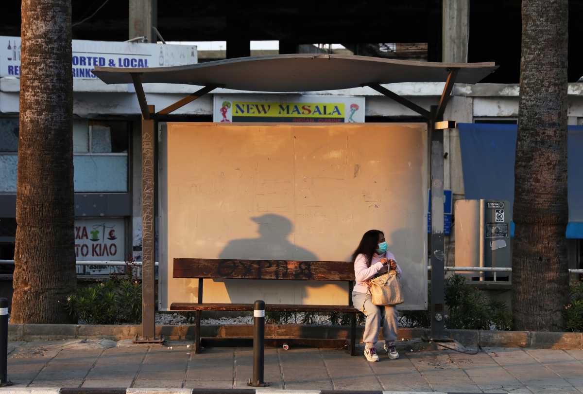 A woman wearing a protective face mask waits at a bus stop amid the coronavirus disease (COVID-19) pandemic, in Nicosia, Cyprus November 29, 2020. REUTERS