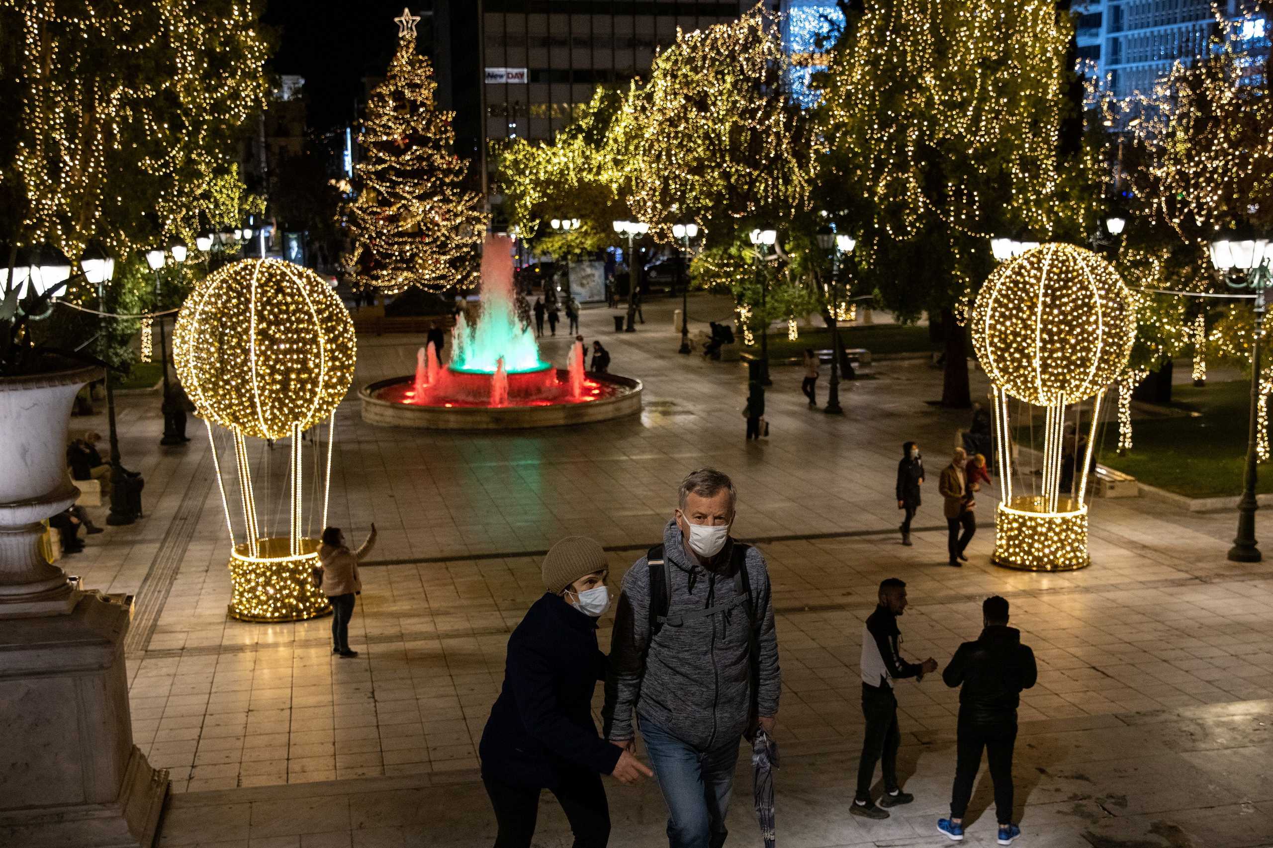 People wearing protective face masks make their way on the Christmas-decorated Syntagma square, during the coronavirus disease (COVID-19) pandemic, in Athens, Greece, December 14, 2020. REUTERS