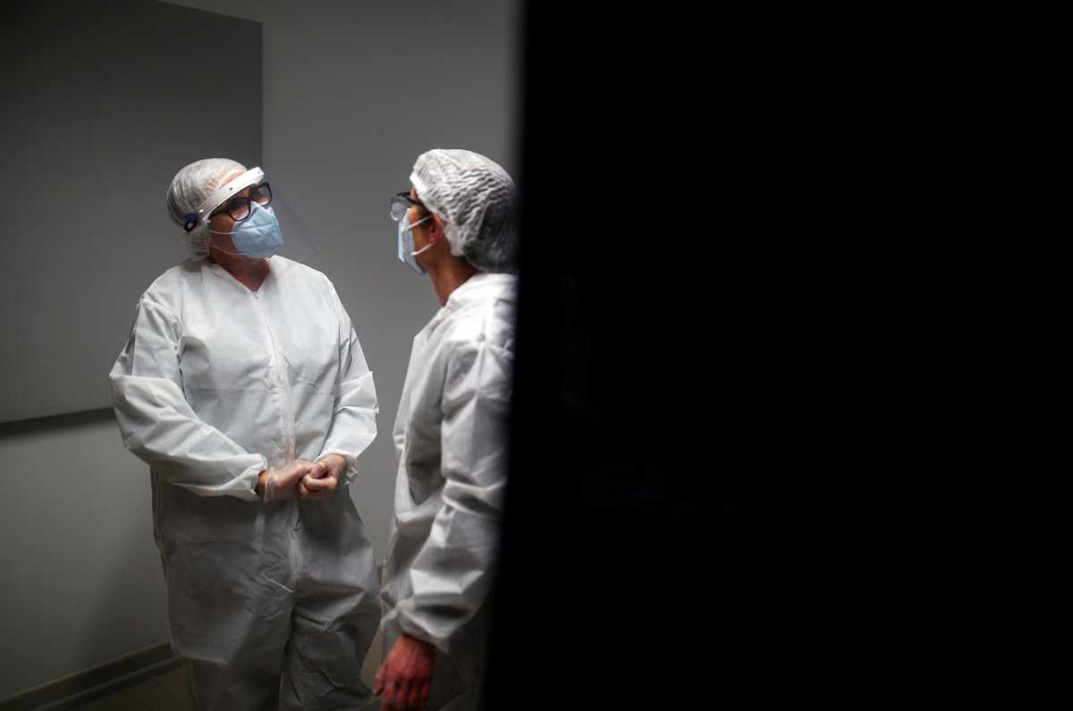 Medical workers, wearing protective suits and face masks, talk as they work at a coronavirus disease (COVID-19) testing centre in Le Bignon, France, December 22, 2020. REUTERS