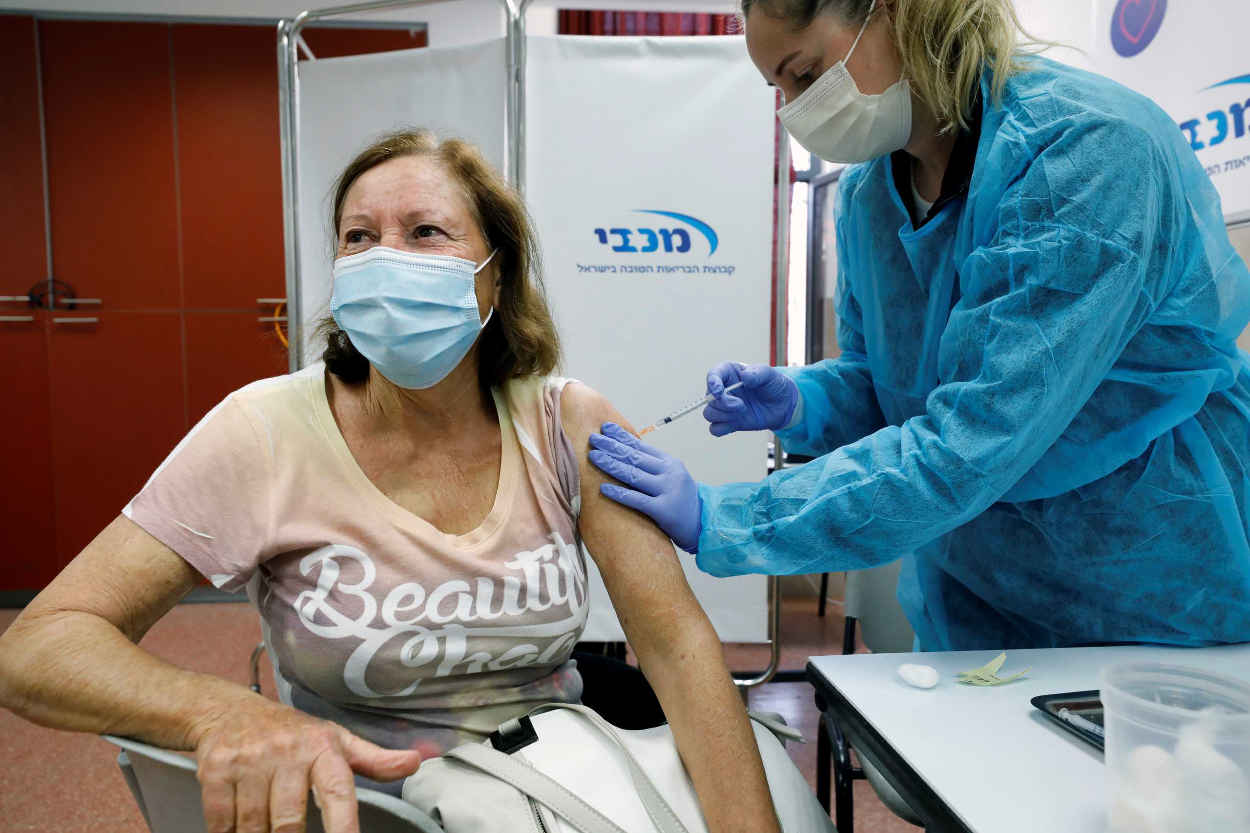 A woman receives a vaccination against the coronavirus disease (COVID-19) as Israel continues its national vaccination drive, during a third national COVID lockdown, at a Maccabi Healthcare Services branch in Ashdod, Israel December 29, 2020. REUTERS