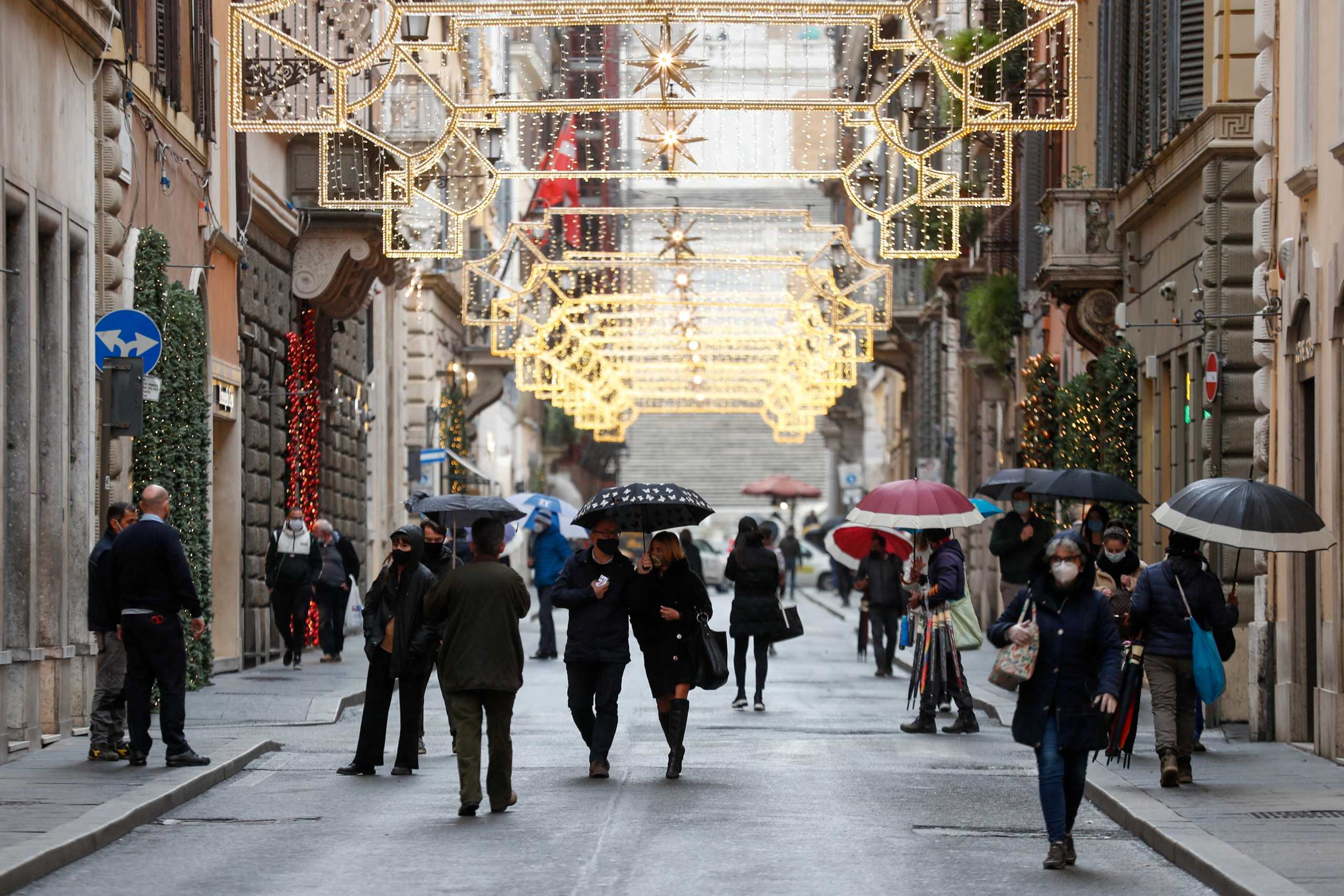 People wearing protective masks walk along Via dei Condotti street on the day Italian Health Minister Roberto Speranza lays out in parliament the government's plan for mass coronavirus disease (COVID-19) vaccinations and restrictions over the Christmas period, in Rome, Italy December 2, 2020. REUTERS