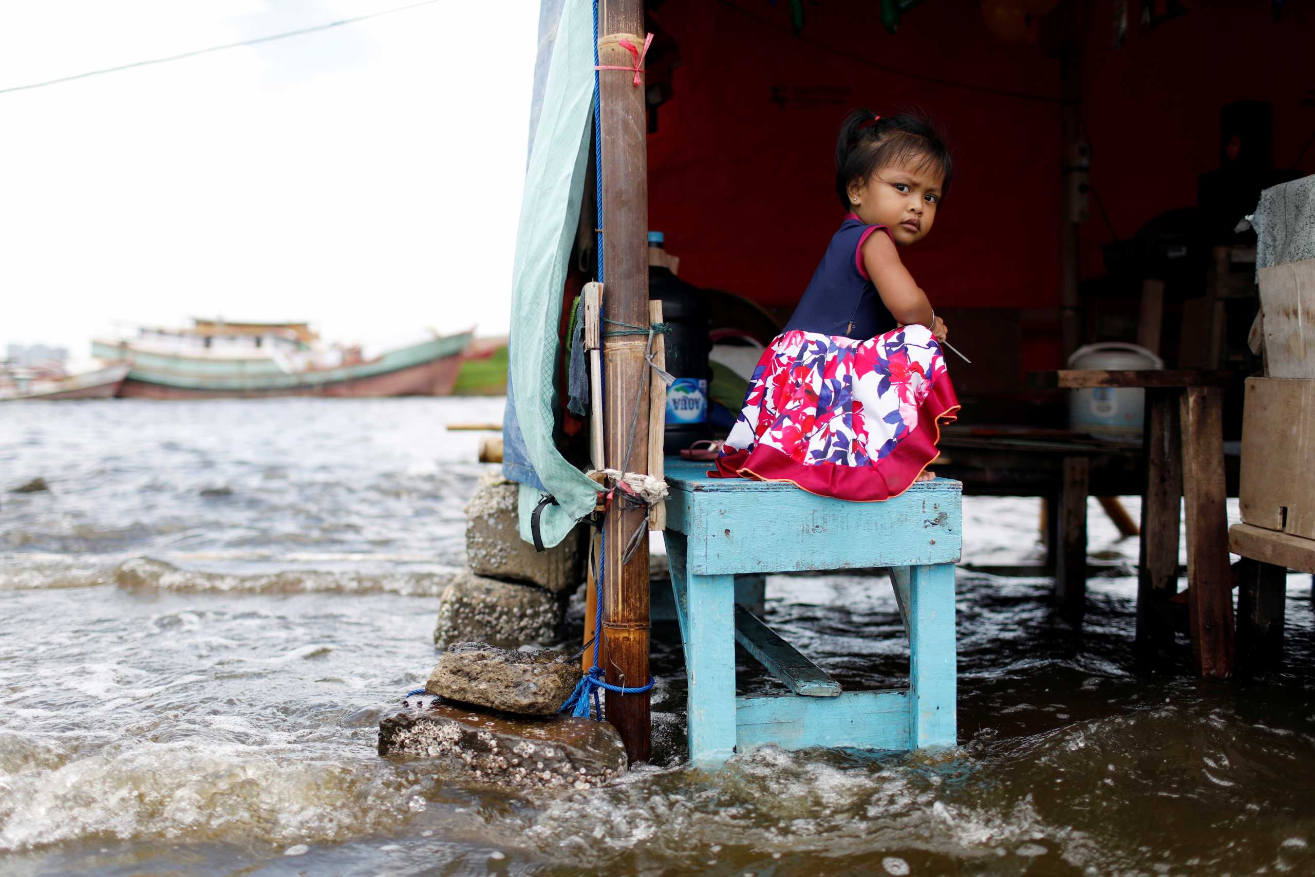 Shaqueena Dwi Arsyilla, 2, sits on a bench at Kali Adem port, which is impacted by high tides due to the rising sea level and land subsidence, north of Jakarta, Indonesia November 20, 2020. REUTERS