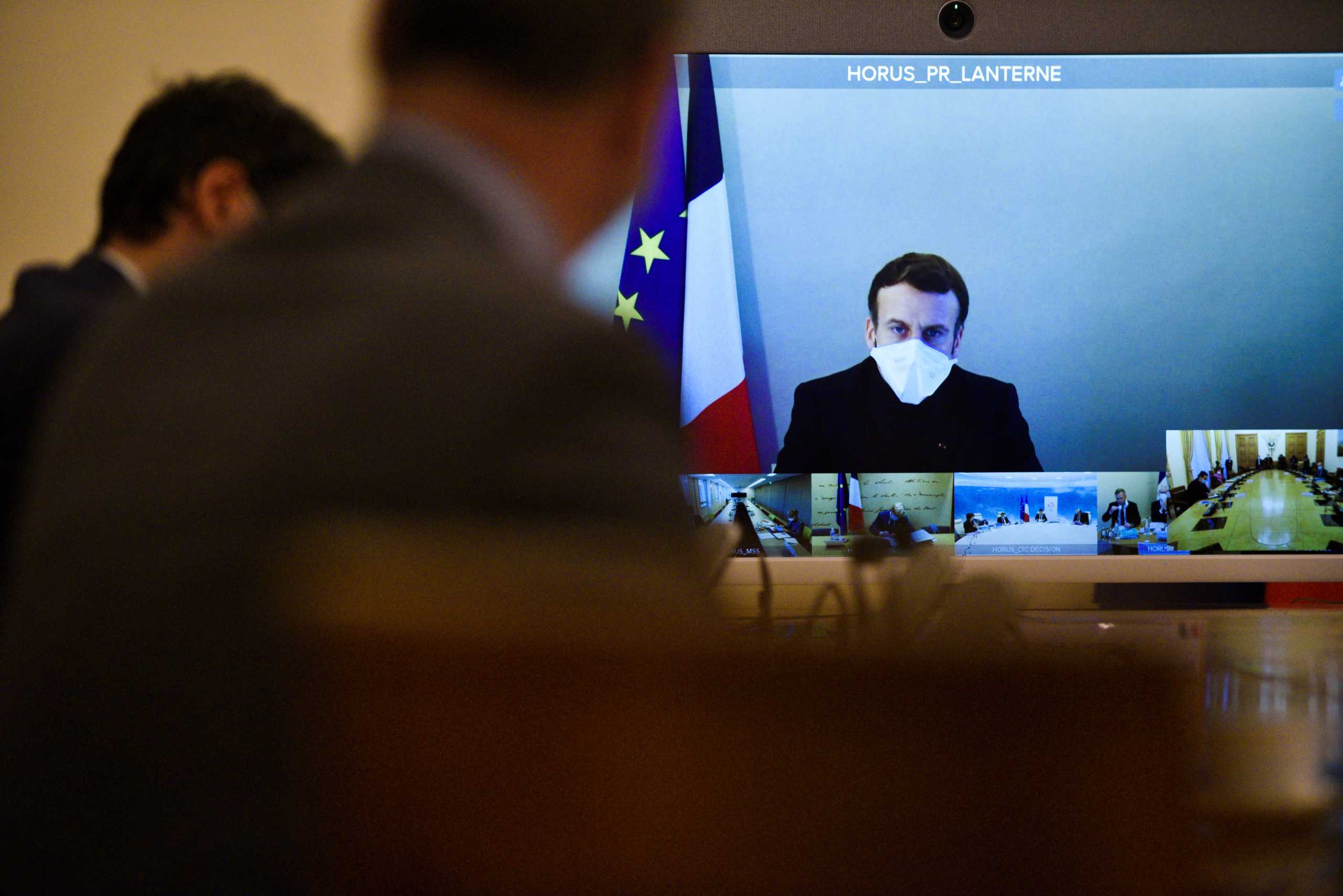 France's President Emmanuel Macron, who tested positive for the coronavirus disease (COVID-19), is seen on a screen as he attends by video conference a round table for the weekly cabinet meeting of the government at the Army Ministry in Paris, France, December 21, 2020.  Julien De Rosa