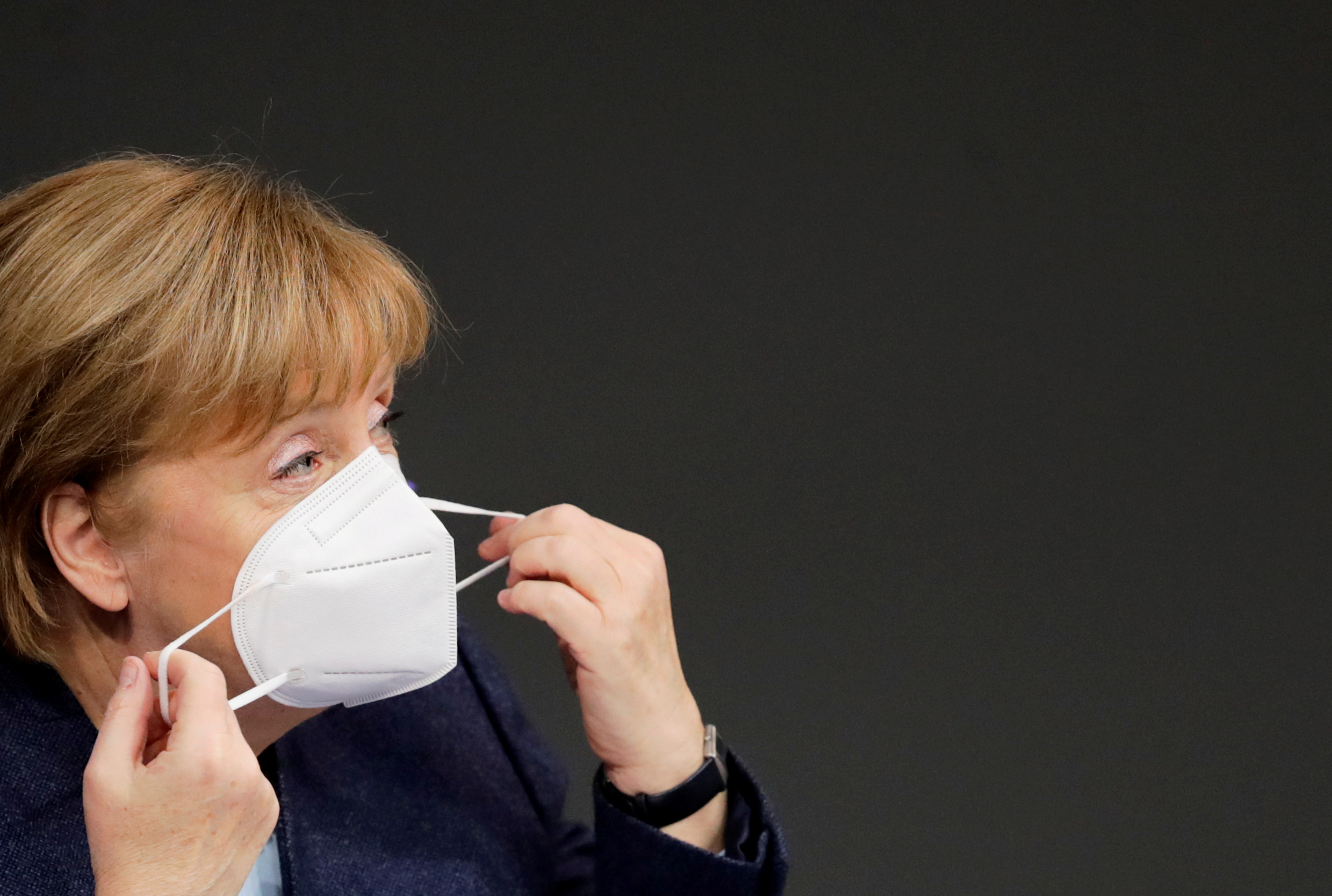 FILE PHOTO: German Chancellor Angela Merkel adjusts her protective mask during a session of the lower house of parliament Bundestag in Berlin, Germany, December 16, 2020. REUTERS
