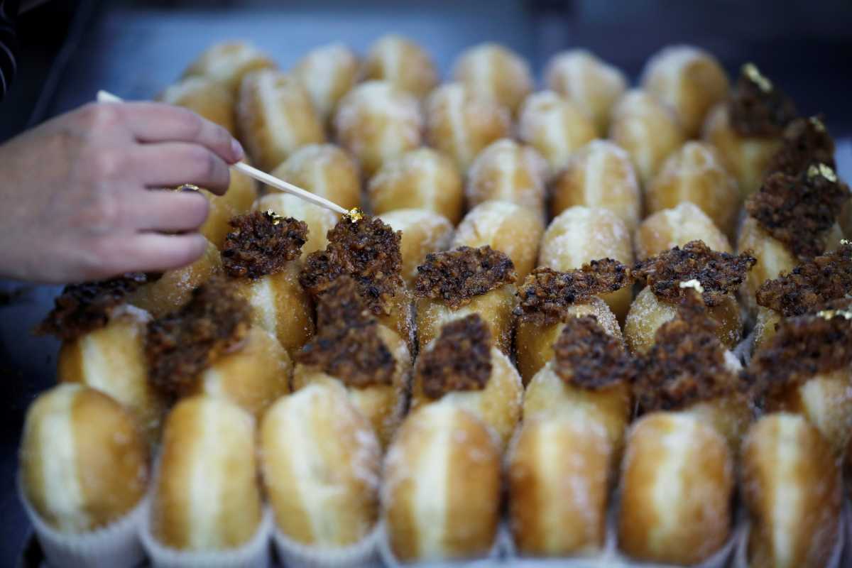A confectioner places a topping on the "Abu Dhabi" doughnut, a date-flavoured confectionery inspired by Israel's new relations with the United Arab Emirates, as doughnuts are a popular fare in Israel during the current holiday of Hanukkah, in which Jews traditionally eat deep-fried delicacies, at a patisserie in Jerusalem December 13, 2020. REUTERS