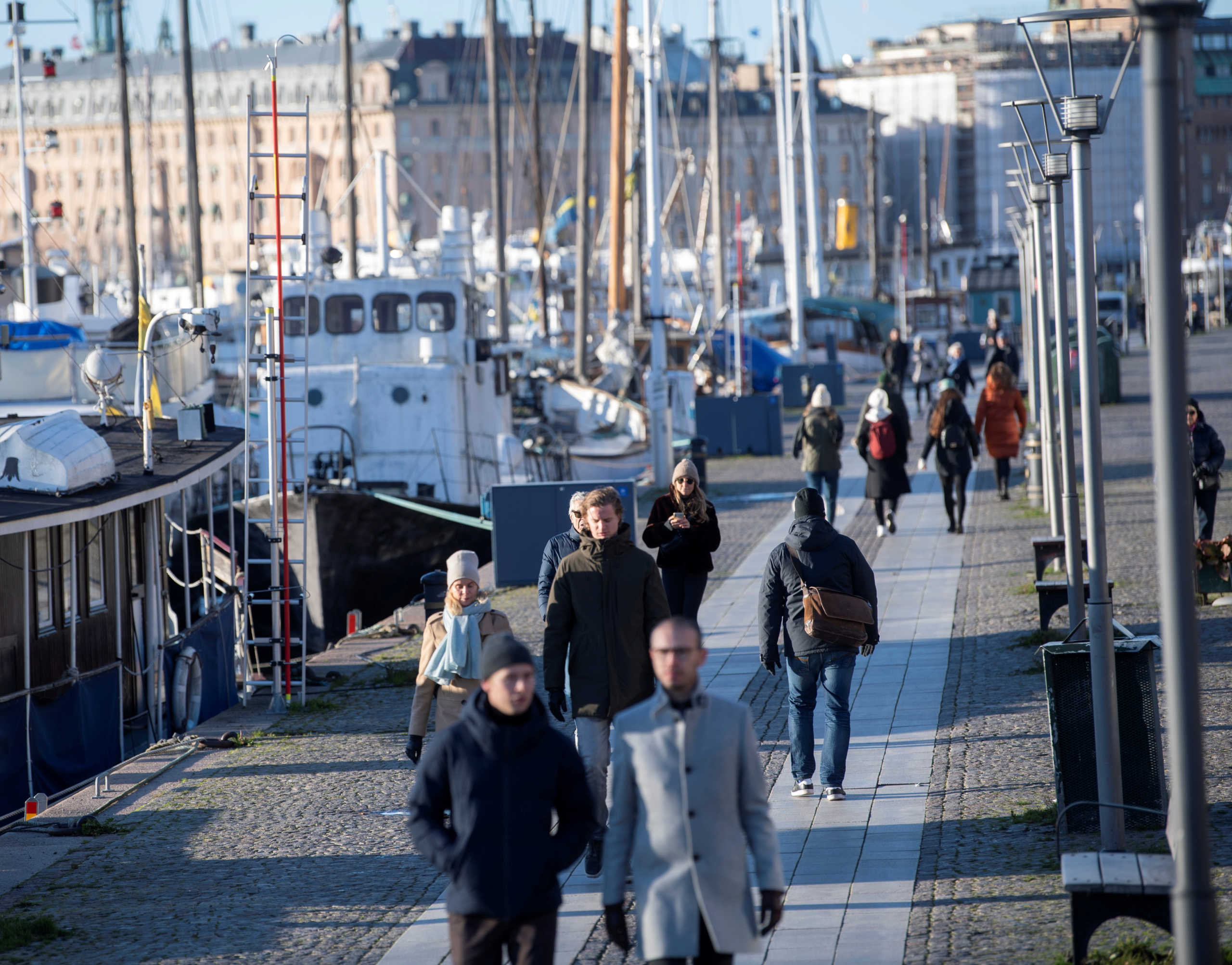 FILE PHOTO: People stroll in the cold but sunny weather along Standvagen quayside, amid the continuous spread of the coronavirus disease (COVID-19) pandemic in Stockholm, Sweden, November 20, 2020. TT News Agency