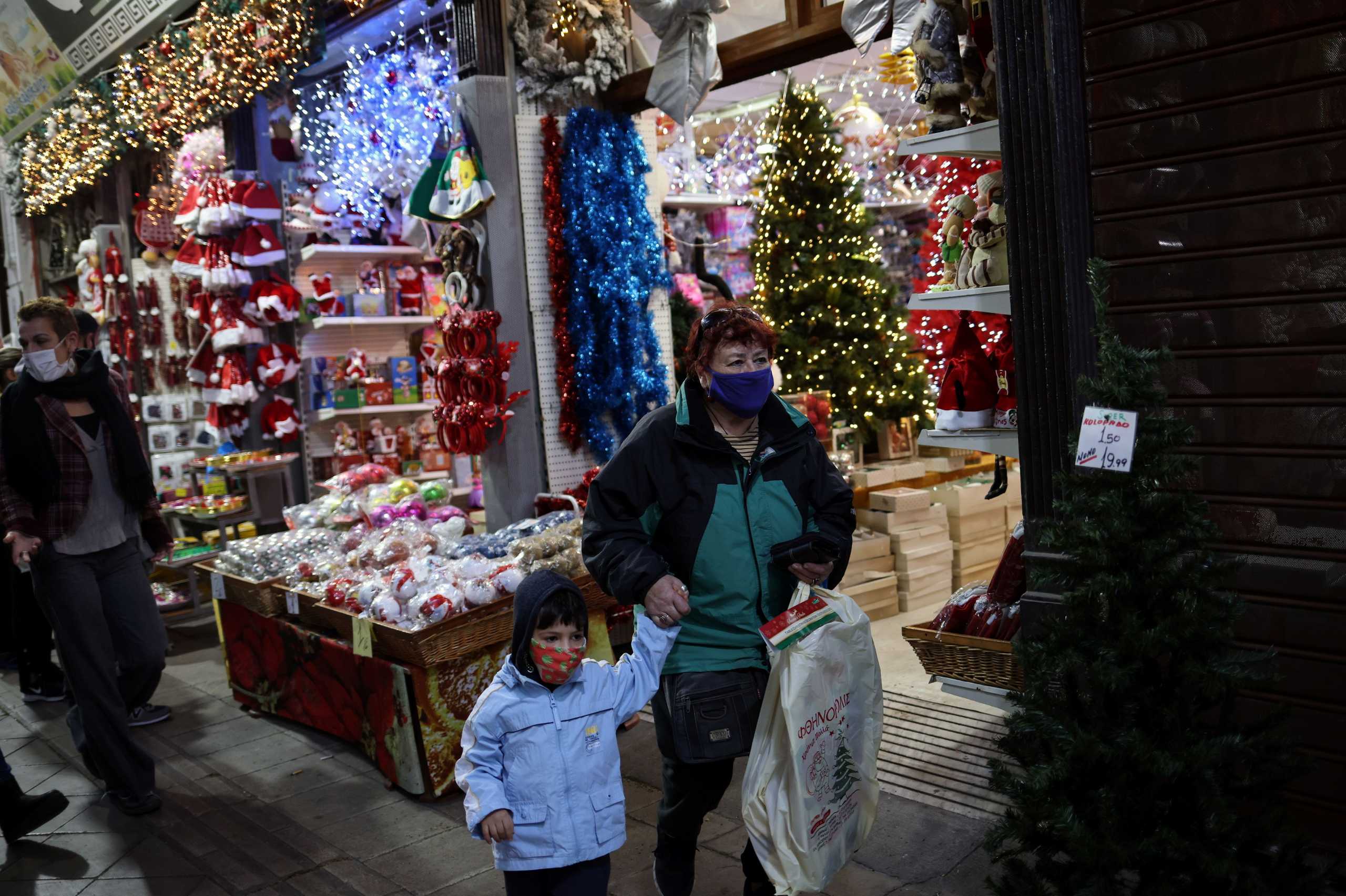 A woman and a boy wearing protective face masks exit a shop selling Christmas decoration products, during the coronavirus disease (COVID-19) pandemic, in Athens, Greece, December 7, 2020. REUTERS