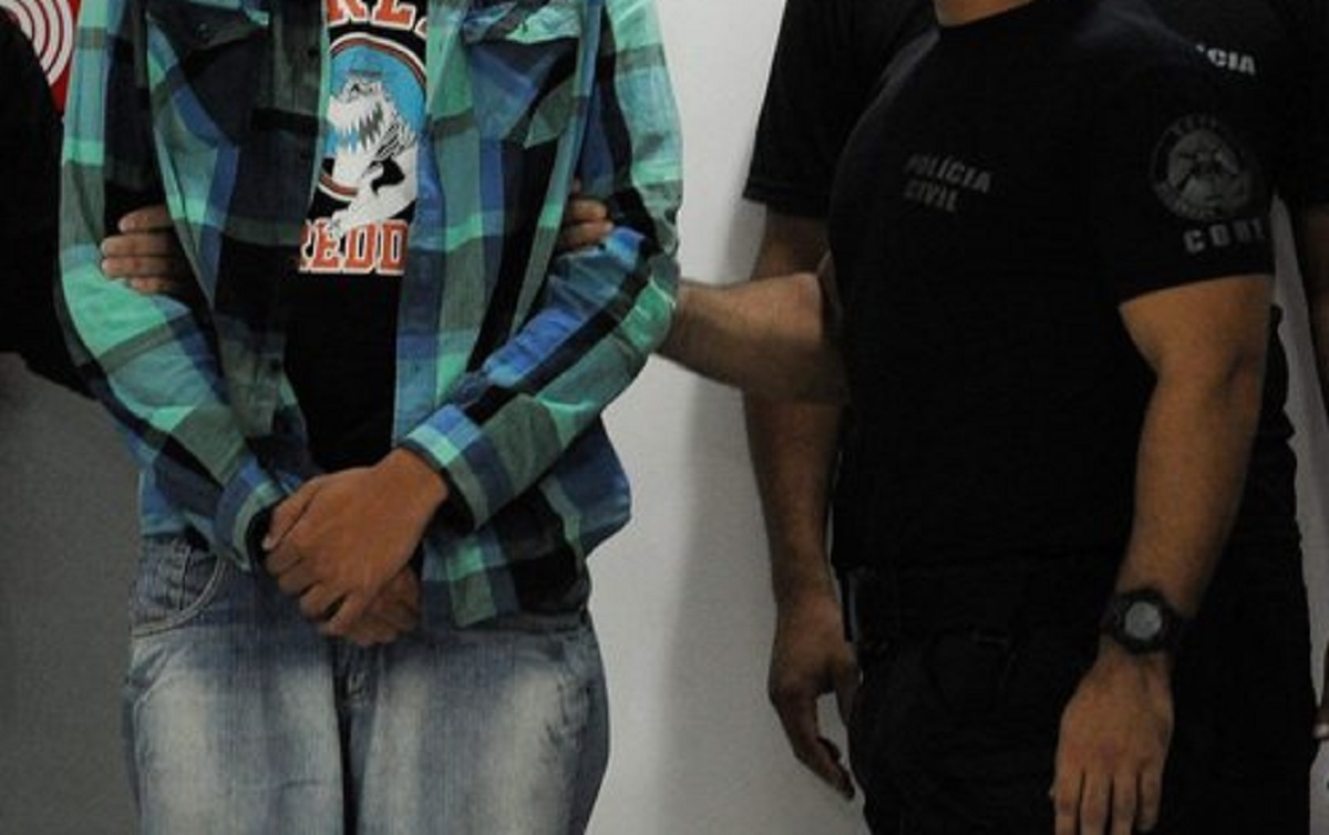 epa04072104 A handout photo released by Brazil Agency shows policemen escorting Caio Silva de Souza (C) at the police headquarter in Rio de Janeiro police, Brazil, 12 February 2014. Brazilian police arrested Caio Silva de Souza, 23 years old, for allegedly throwing a bengal light that injured and then caused the death of TV cameraman Santiago Andrade during a protest against high fares of autobus in Rio de Janeiro.  EPA