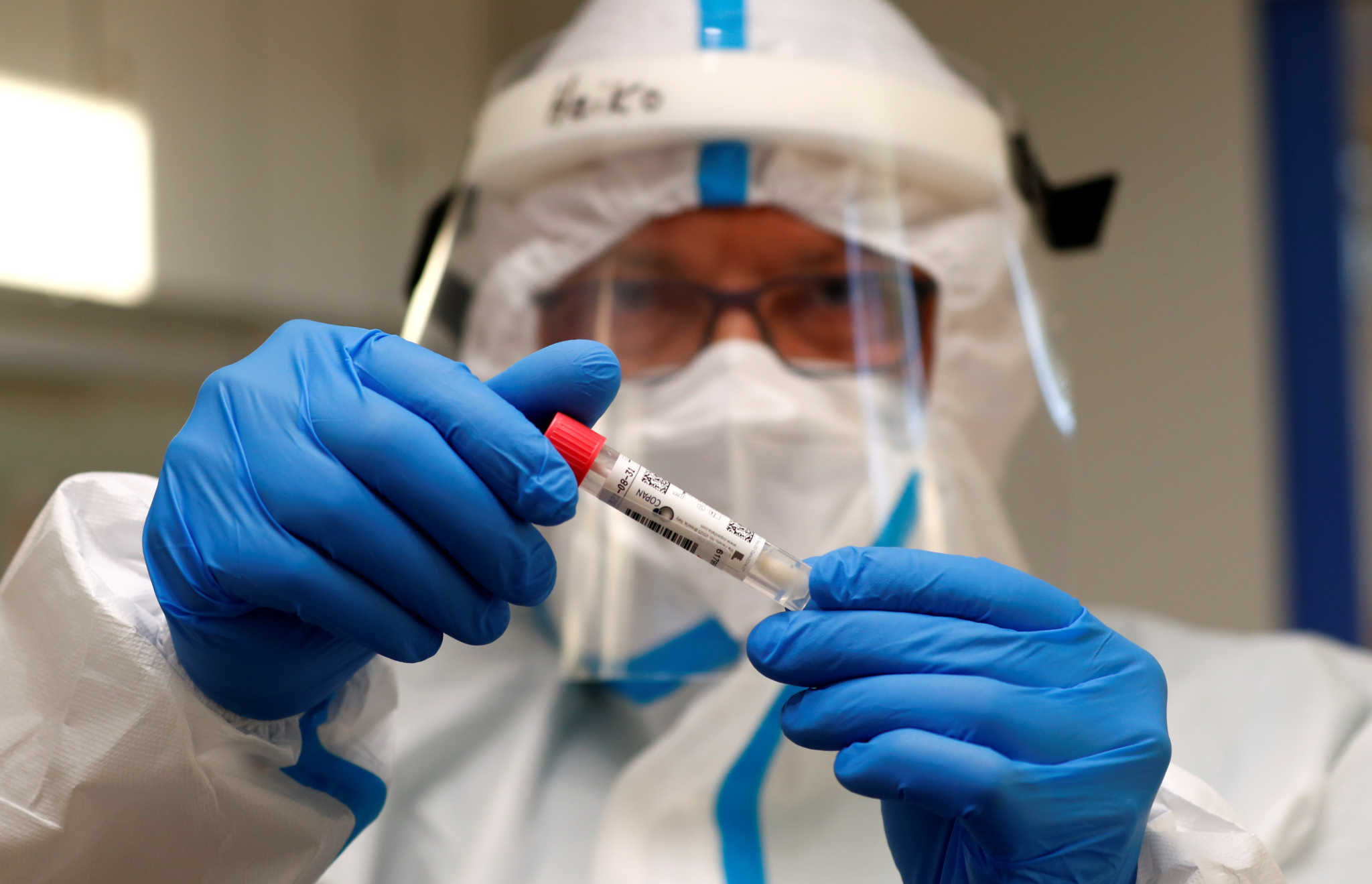 A German Red Cross medical staff holds a smear-test stick of a traveller who returned from the Ukraine, after a voluntary coronavirus disease (COVID-19) test at the new Corona test station of the central bus location in Berlin, Germany, August 5, 2020.      REUTERS