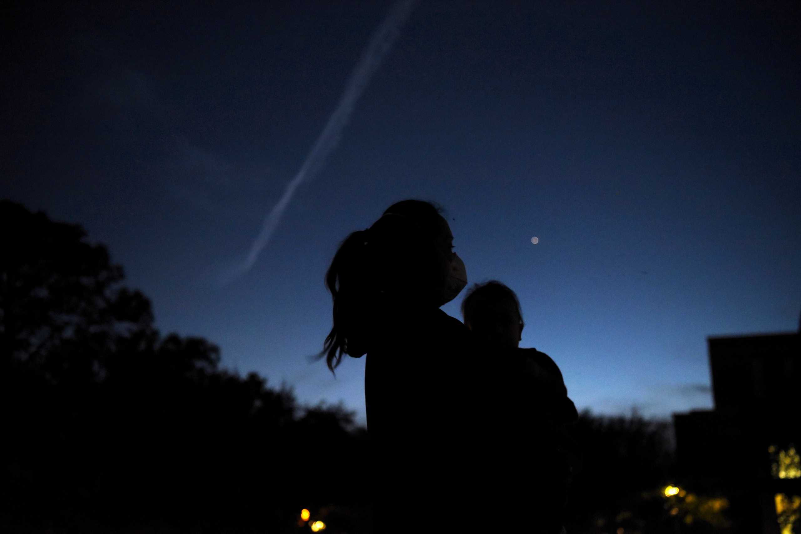 Thao Galvan holds her son Nathan while they view Jupiter and Saturn during a planetary conjuction, as they appear close together in a rare celestial event in Houston, Texas, U.S., December 21, 2020. REUTERS