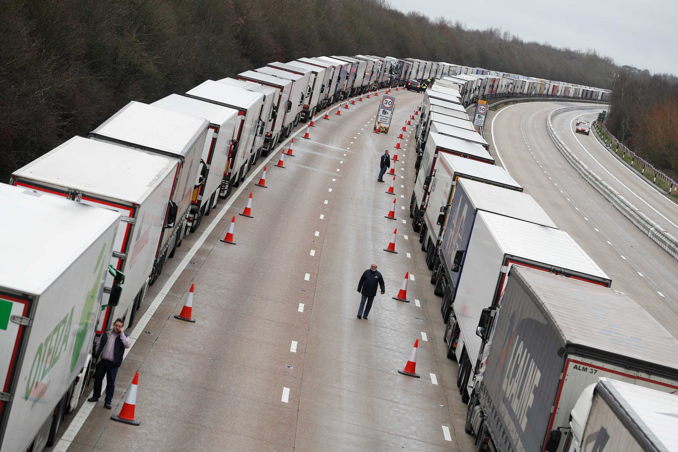People walk amid lines of lorries queueing at the M20 motorway near Ashford amid the coronavirus disease (COVID-19) outbreak, Britain, December 26, 2020. REUTERS