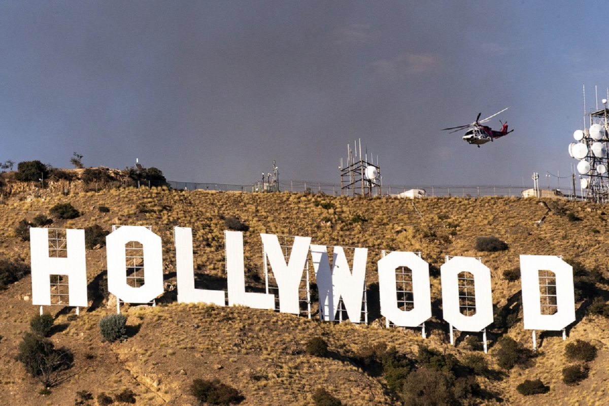 epa07985082 A firefighting helitanker flies above the Hollywood Sign as smoke of the Barham Fire rises from in the hills behind in Los Angeles, California, USA, 09 November 2019. According to latest media reports the fire burnt 25 acres and is now contained.  EPA