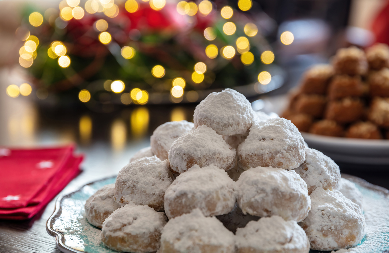 Christmas Greek desserts. Traditional homemade kourambiedes plate, bokeh Xmas lights decoration background, closeup view