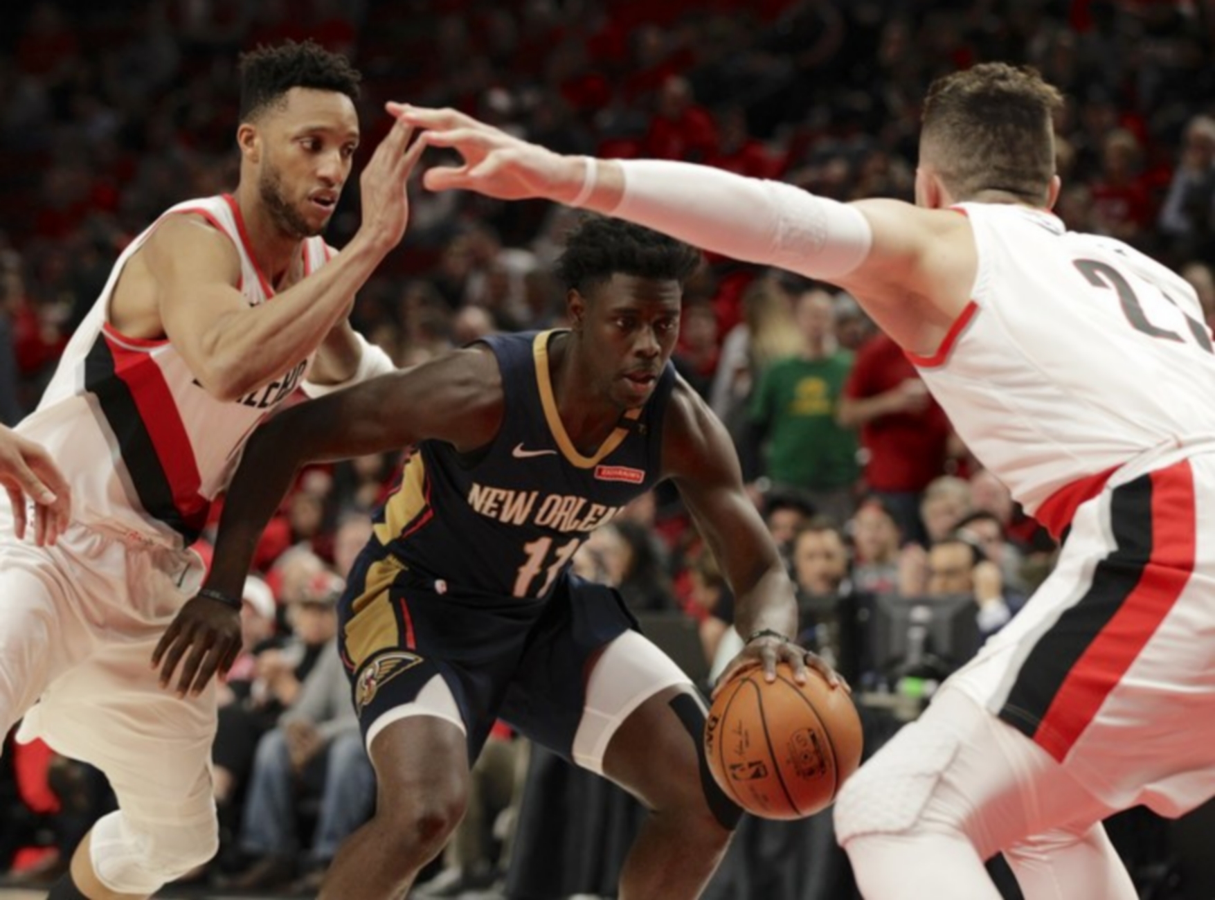 epa06676140 New Orleans Pelicans guard Jrue Holiday (C) splits the defense of Portland Trail Blazers forward Evan Turner (L) and Portland Trail Blazers center Jusuf Nurkic (R) of Bosnia in the second half of their Western Conference First Round NBA game at the Moda Center in Portland, Oregon, USA, 17 April 2018.  EPA