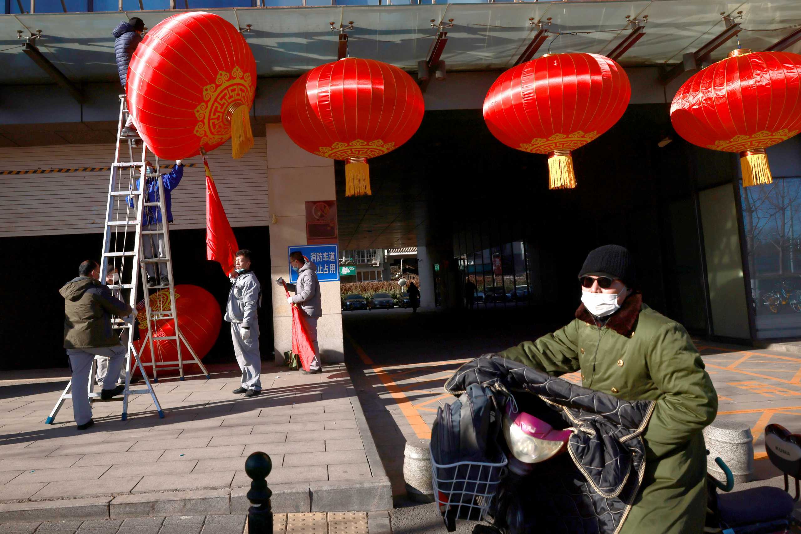 Men hang red lanterns marking New Year and Lunar New Year festivities following the outbreak of the coronavirus disease (COVID-19) in Beijing, China December 31, 2020. REUTERS