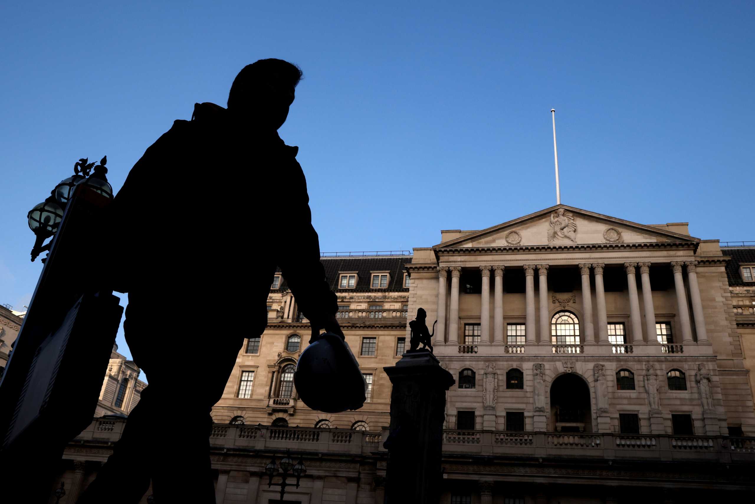 FILE PHOTO: A person is silhouetted as he walks past the Bank of England, amid the outbreak of the coronavirus disease (COVID-19), in London, Britain, November 5, 2020. REUTERS