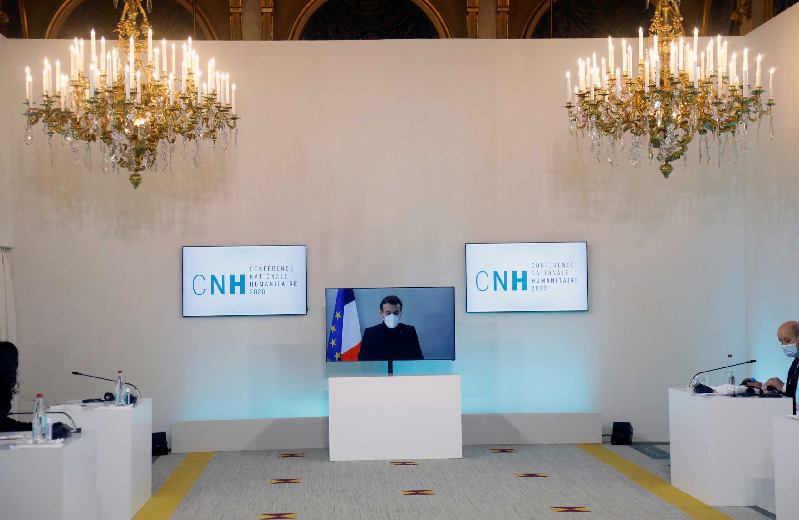 French President Emmanuel Macron, tested positive for the coronavirus disease (COVID-19), is seen on a screen as he attends by video conference a round table for the National Humanitarian Conference (NHC) at the Foreign Affairs Ministry in Paris, France, December 17, 2020. REUTERS