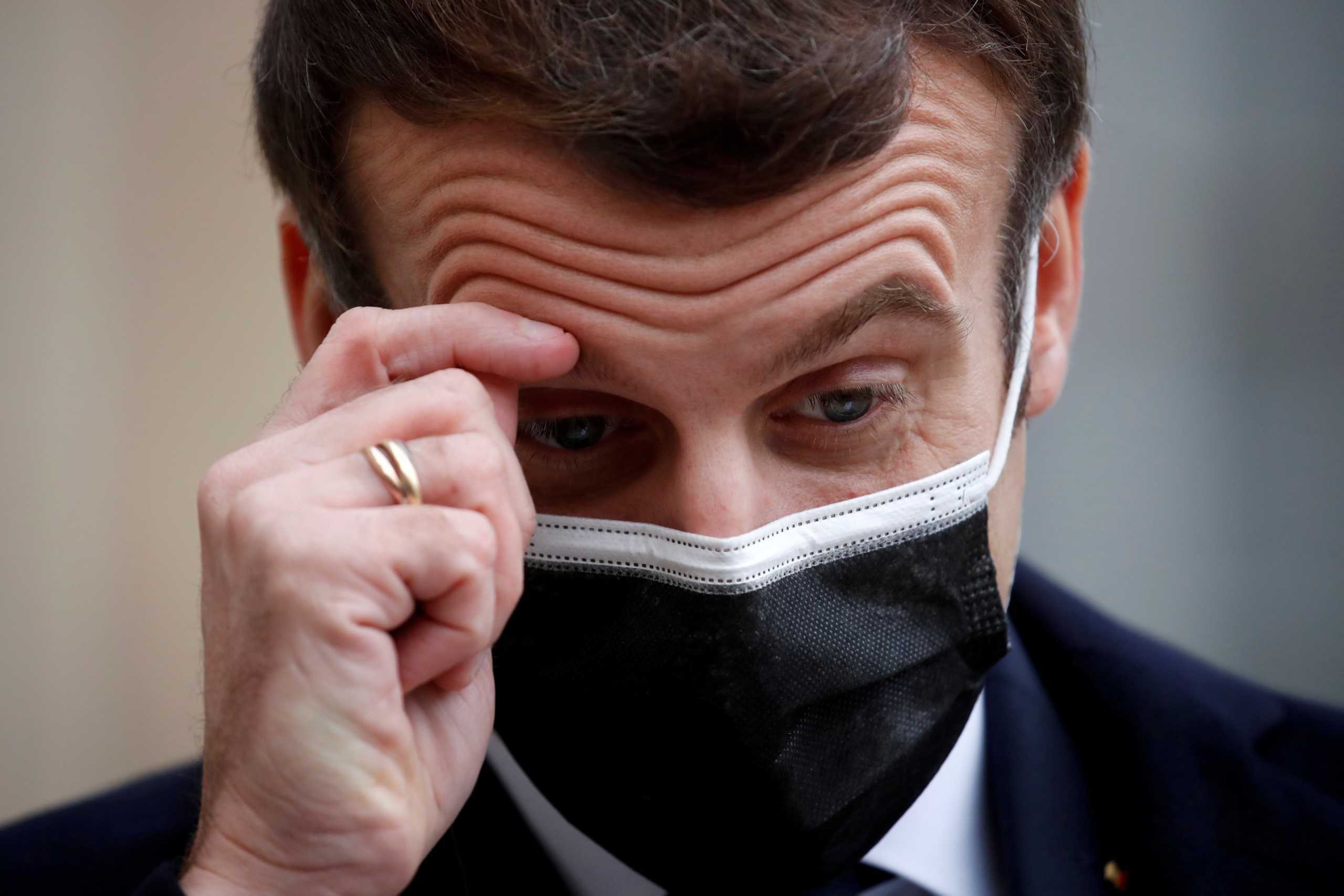 FILE PHOTO: French President Emmanuel Macron, wearing a protective face mask, scratches his brow as he talks to the media next to Portugal's Prime Minister Antonio Costa (not seen) before a meeting at the Elysee Palace in Paris, France, December 16, 2020. REUTERS