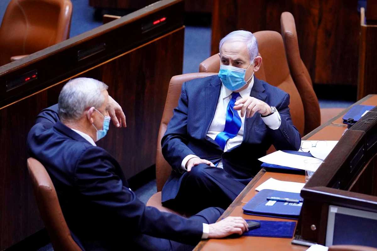 FILE PHOTO: Israeli Prime Minister Benjamin Netanyahu and Benny Gantz, centrist Blue and White leader, and Netanyahu's partner in his new unity government, wear face masks as they talk during a swearing in ceremony of the new government, at the Knesset, Israel's parliament, in Jerusalem May 17, 2020. Amos Ben Gershon